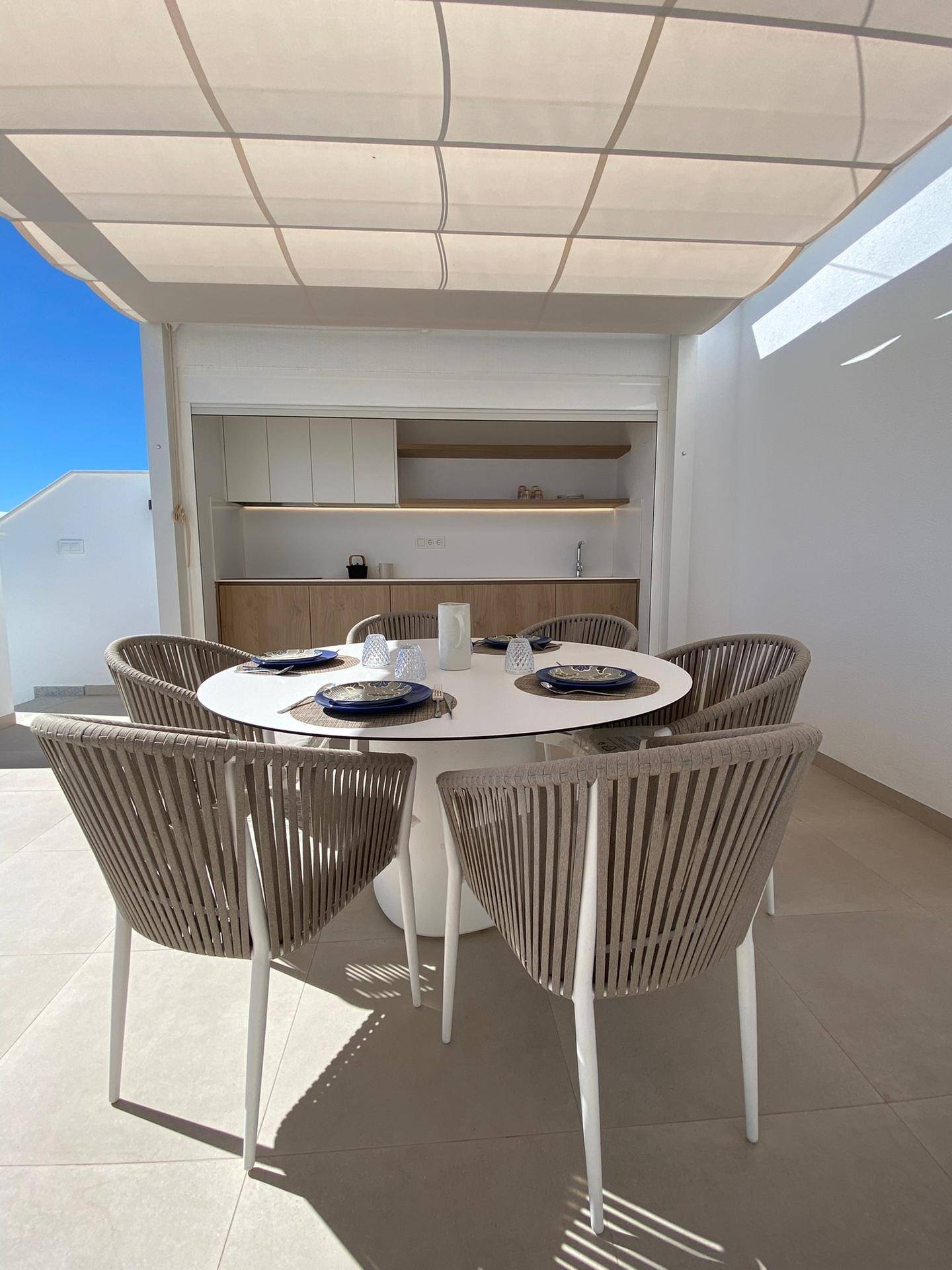Geräumige Dachterrasse mit Essbereich, Sonnenschutz und integrierter Außenküche.