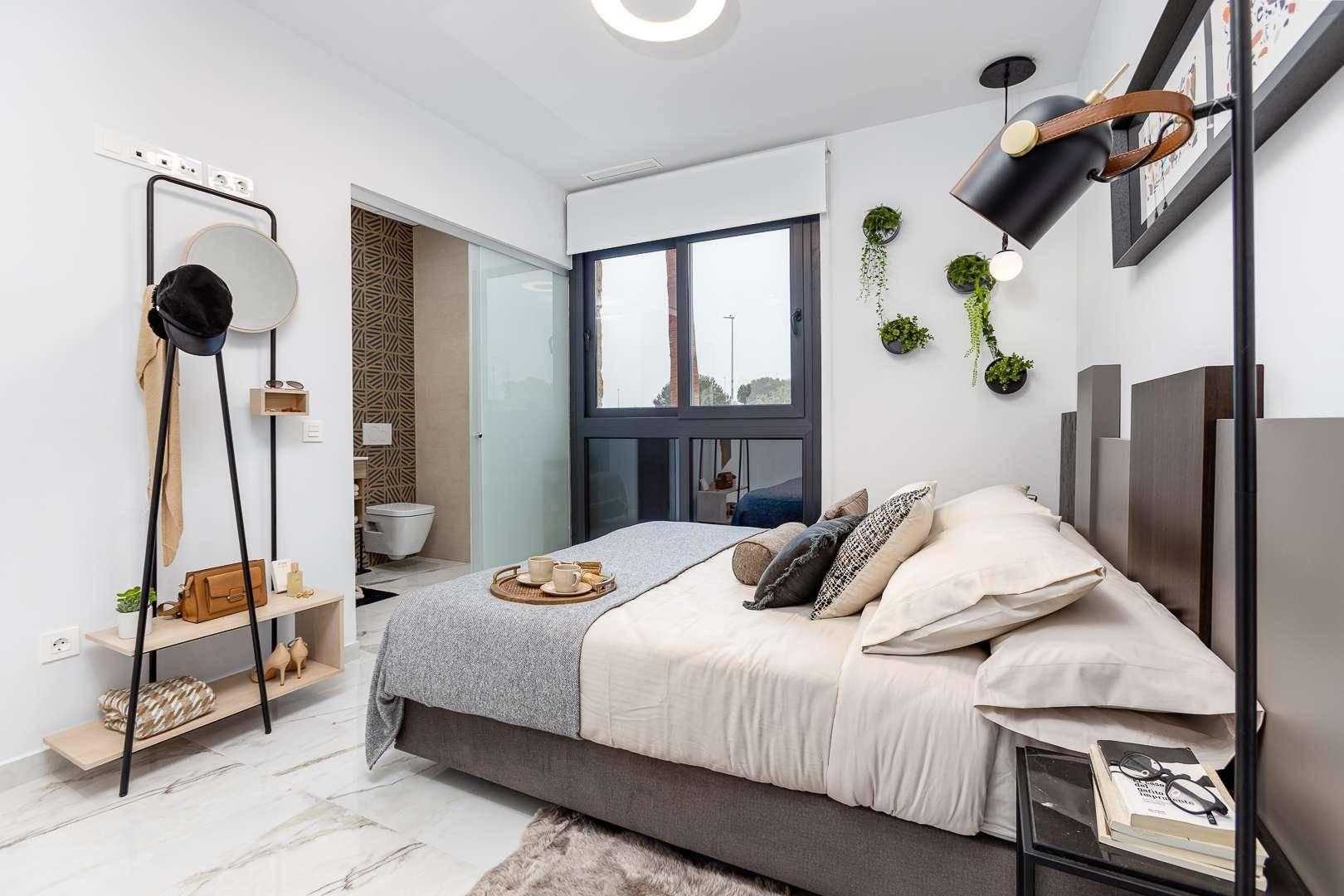 Stilvolles Schlafzimmer mit Doppelbett, Garderobe und direktem Zugang zum Badezimmer.