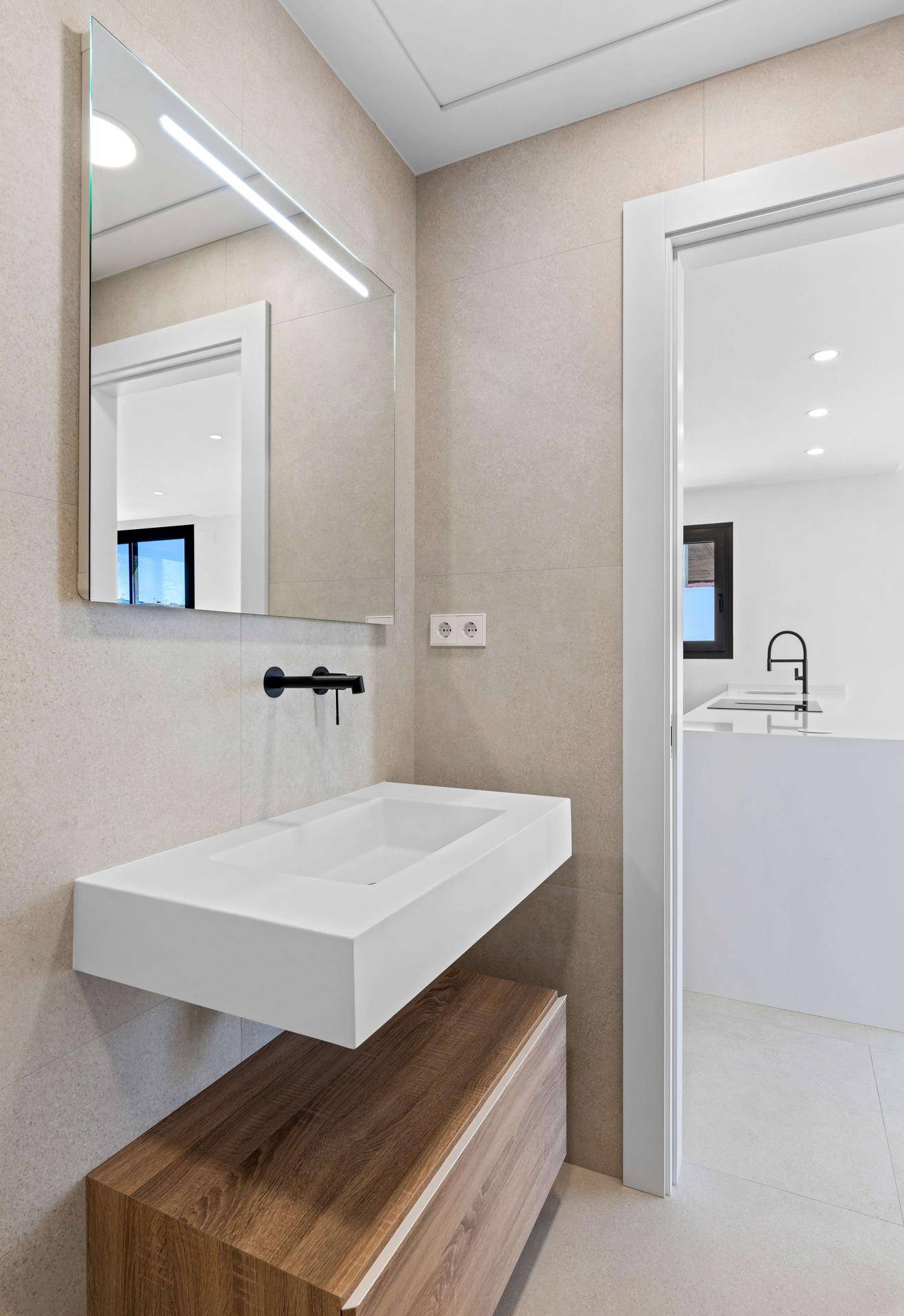Elegantes Badezimmer mit schwebendem Waschtisch, Spiegel und Blick in die Küche.