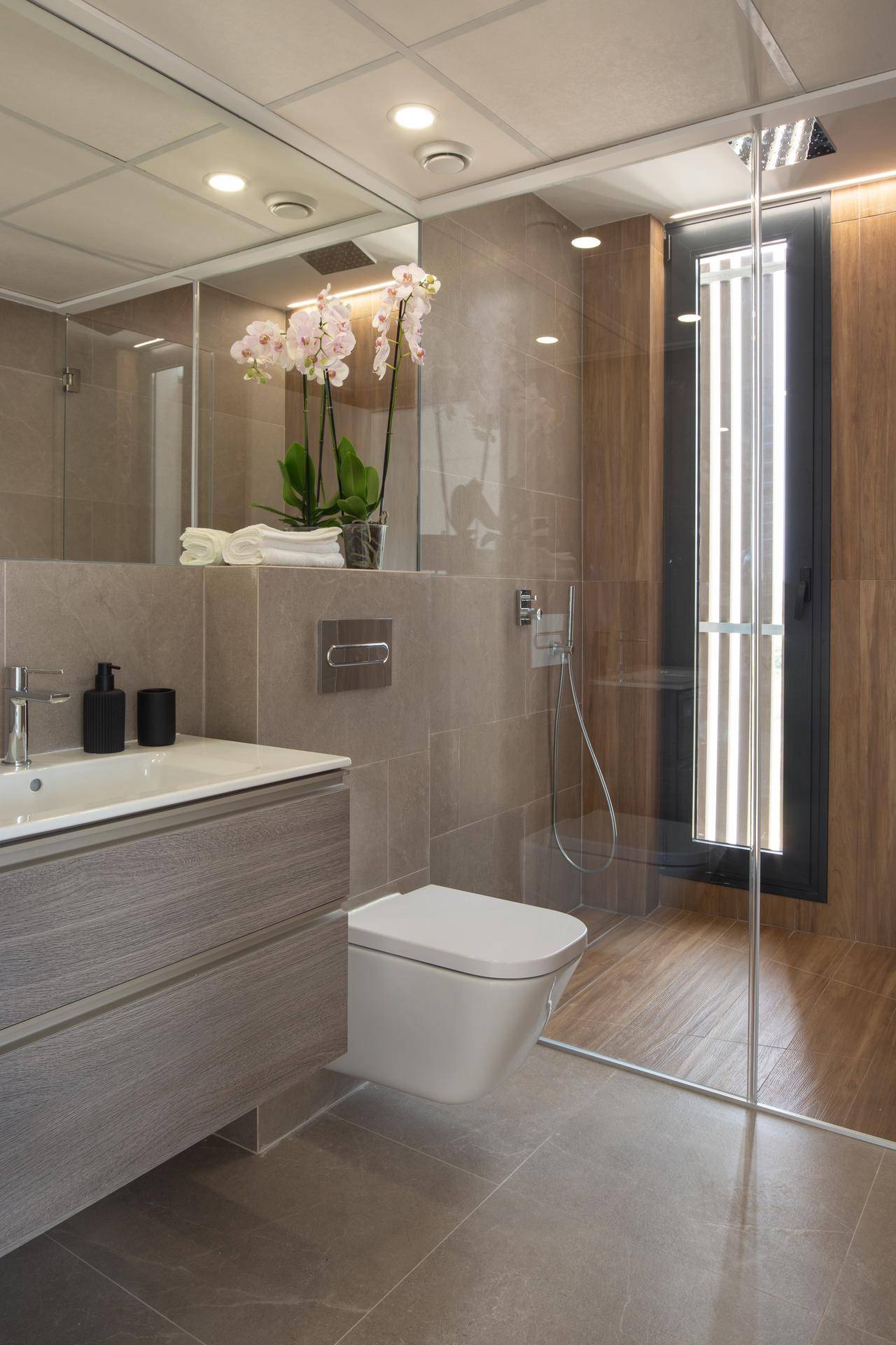Modernes Badezimmer mit begehbarer Dusche, schwebender Toilette und eleganten Fliesen.