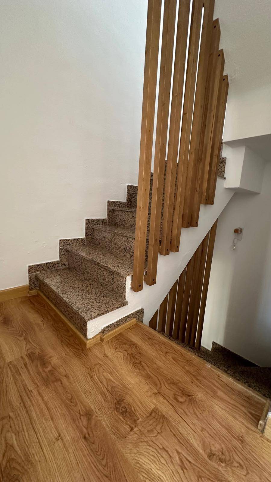 Treppenhaus mit Granitstufen und Holzgeländer, führt zu den oberen Etagen.