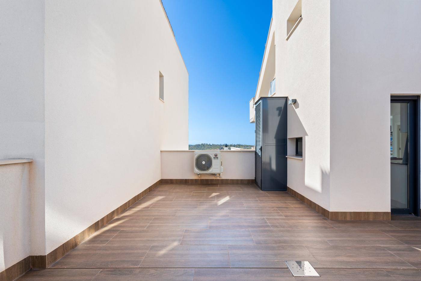 Sonniger Terrassenbereich mit Klimaanlage und Blick auf die Umgebung.