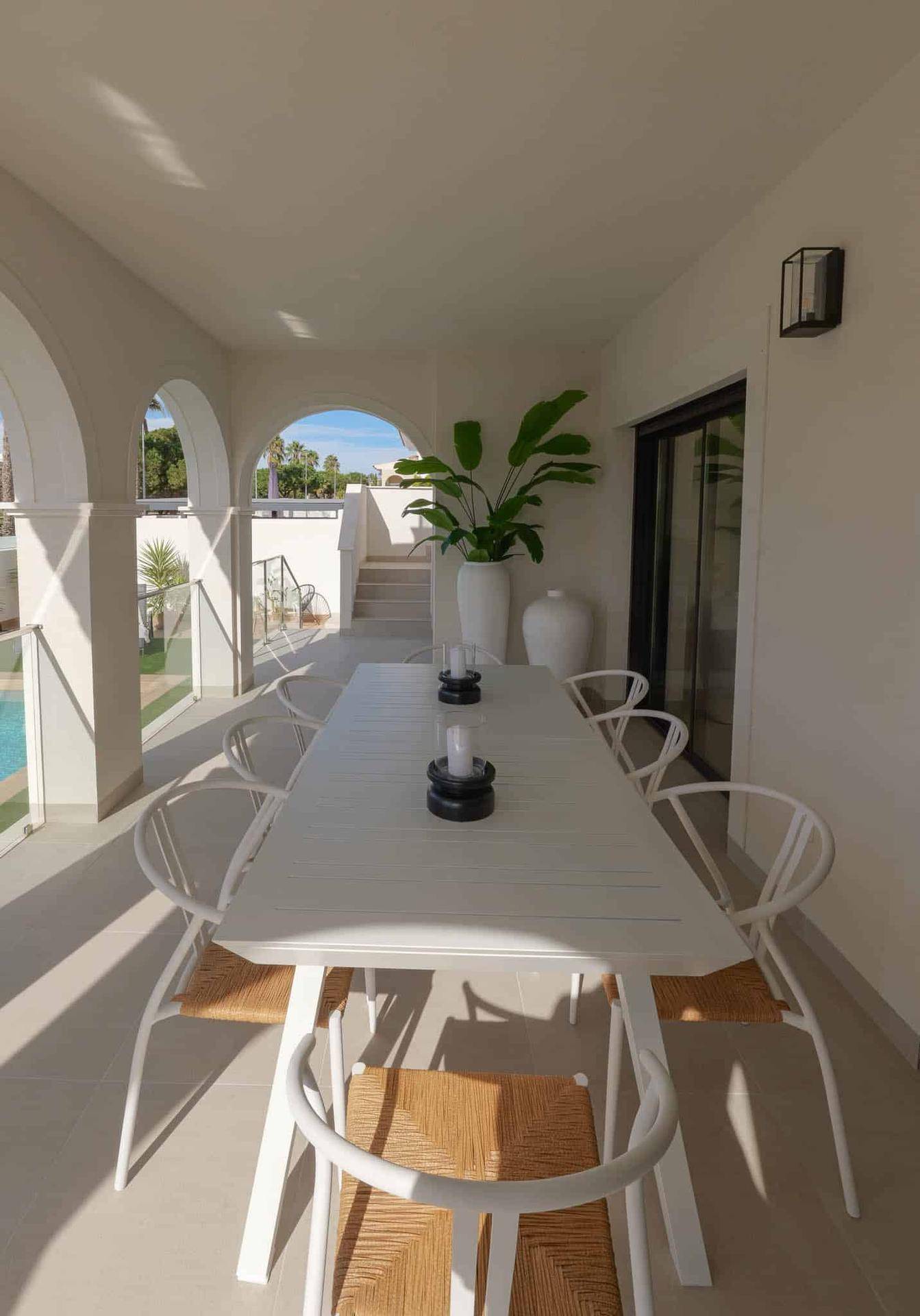 Stilvolle überdachte Terrasse mit modernem Esstisch und Blick auf den Außenbereich der Villa.