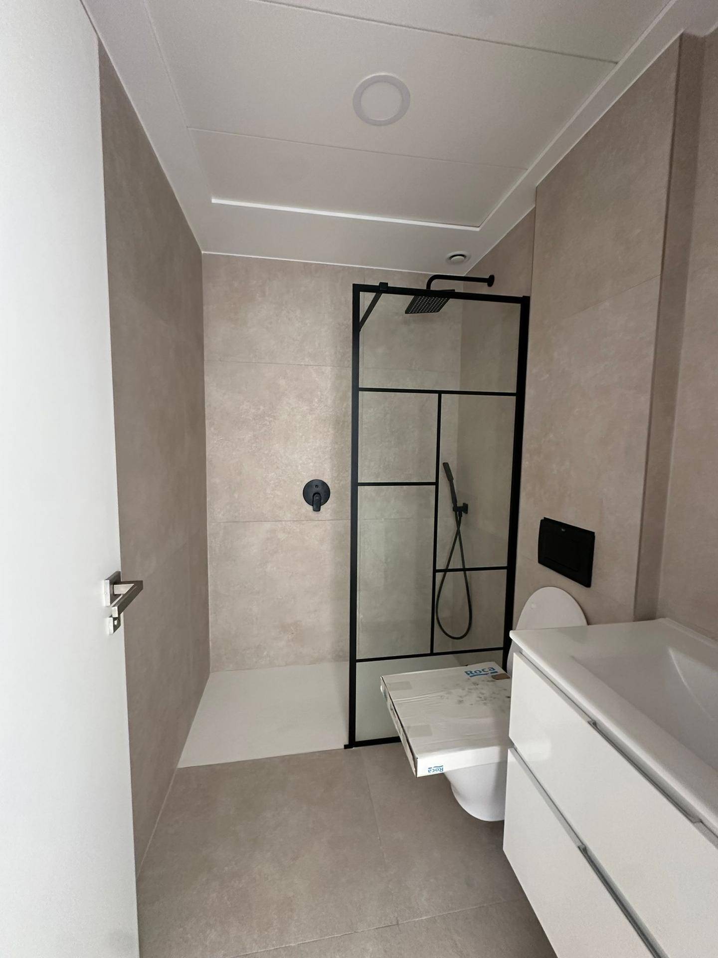 Modernes Badezimmer mit begehbarer Dusche, Wand-WC und hellen Fliesen.
