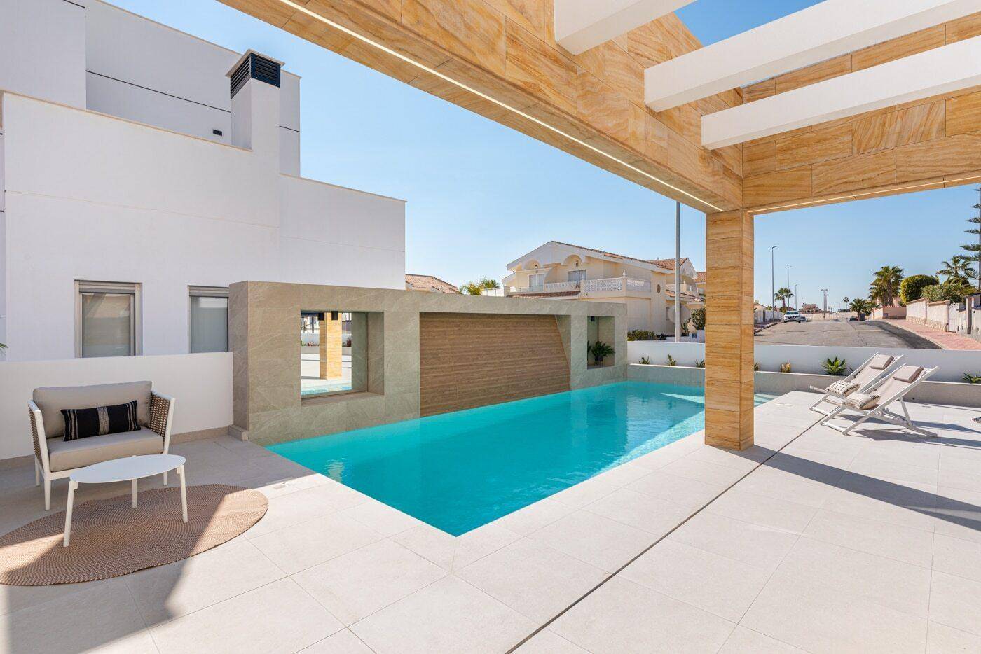 Geräumige Poolterrasse mit Liegestühlen und moderner Architektur im Hintergrund.