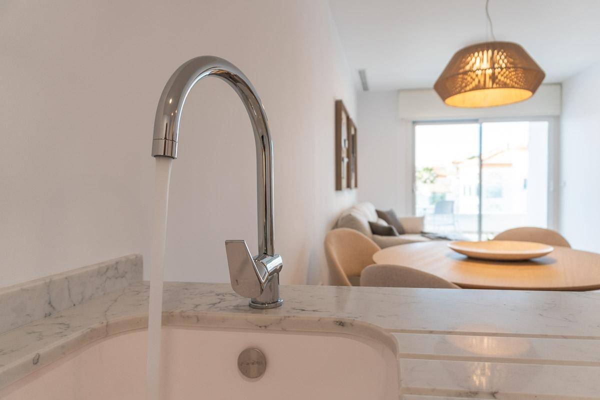Moderner Wasserhahn und Spülbecken in einer hellen Küche mit offener Wohnraumgestaltung.