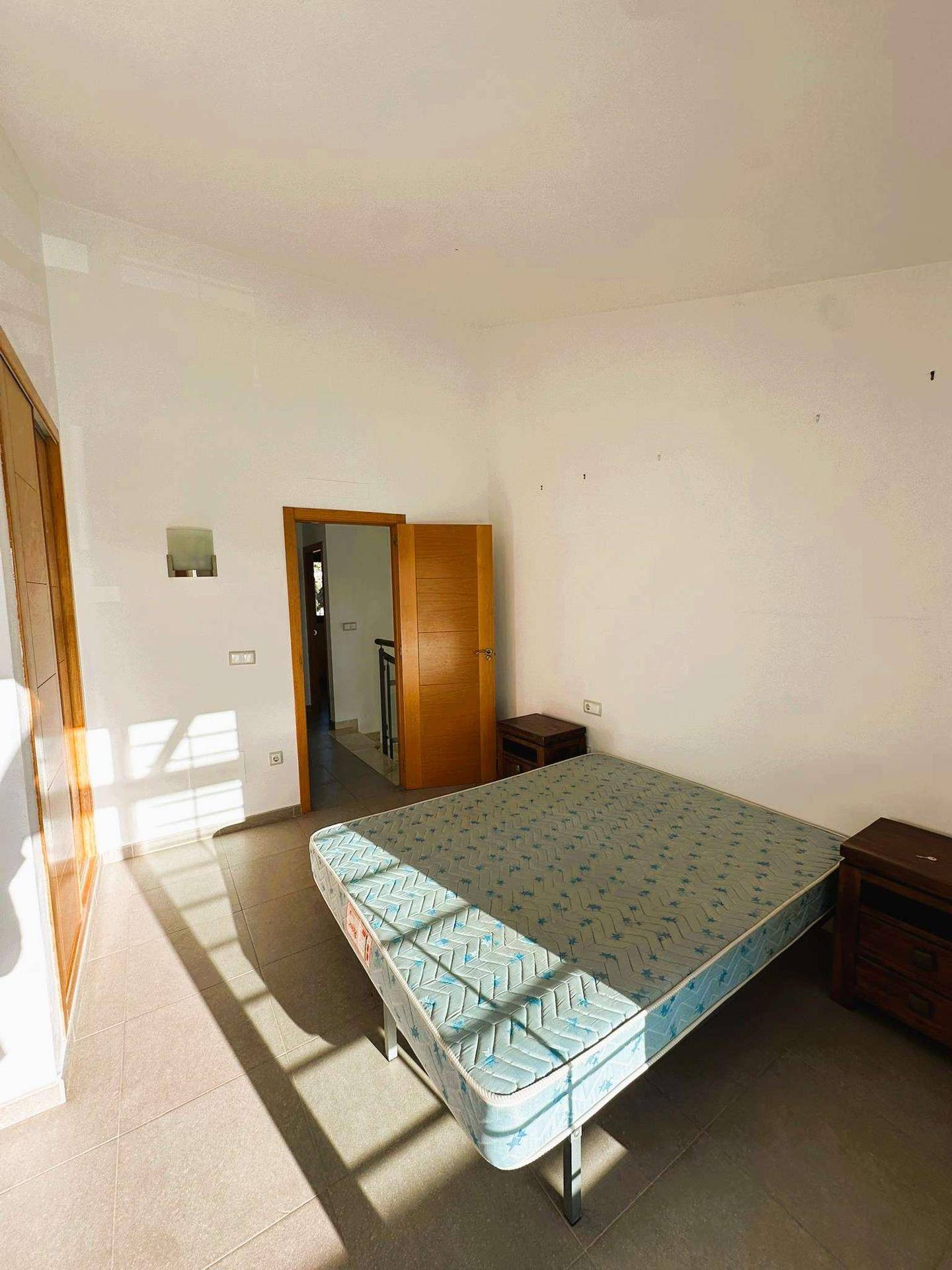 Geräumiges Schlafzimmer mit Fliesenboden und Zugang zum Flur, durchflutet von Sonnenlicht.
