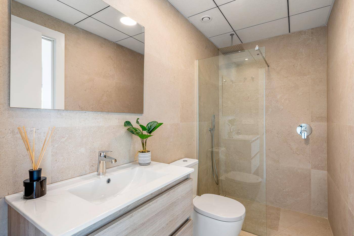 Modernes Badezimmer mit begehbarer Dusche, Waschtisch und Wandfliesen in Natursteinoptik.