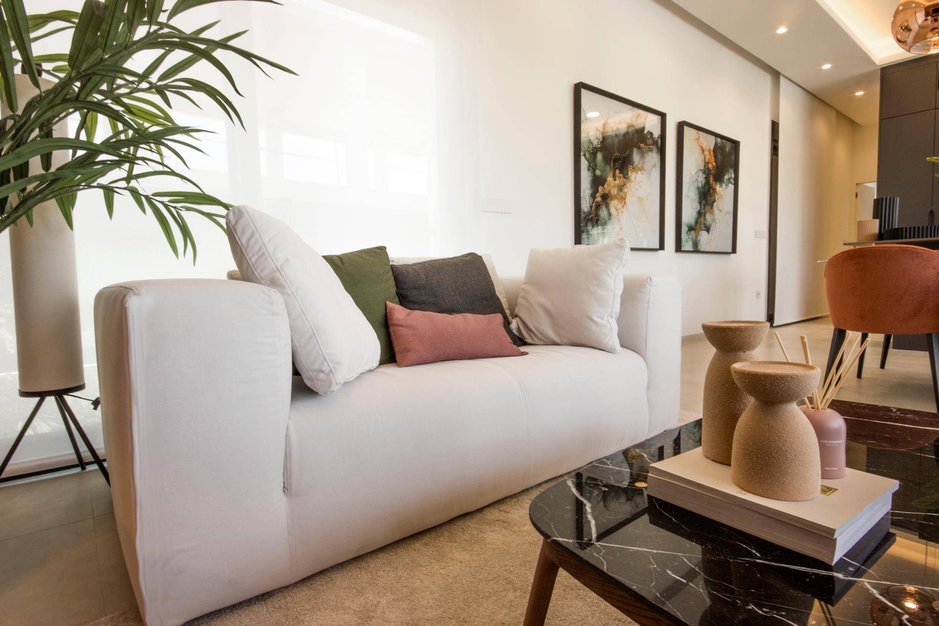 Gemütliches Wohnzimmer mit weißem Sofa, modernen Bildern und Pflanzenakzenten.