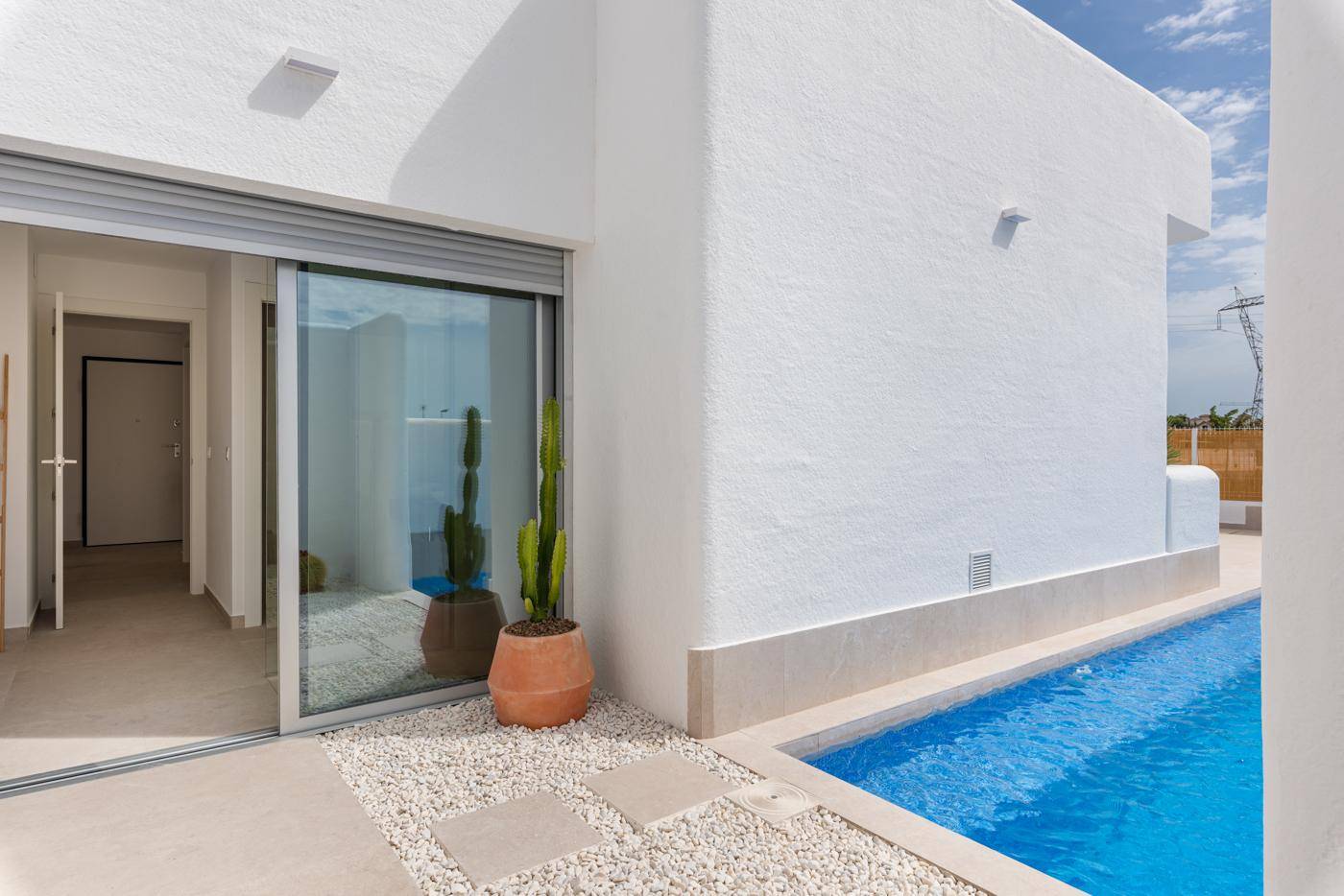 Seitlicher Terrassenbereich mit Schiebetür zum Innenraum und Blick auf den Pool.