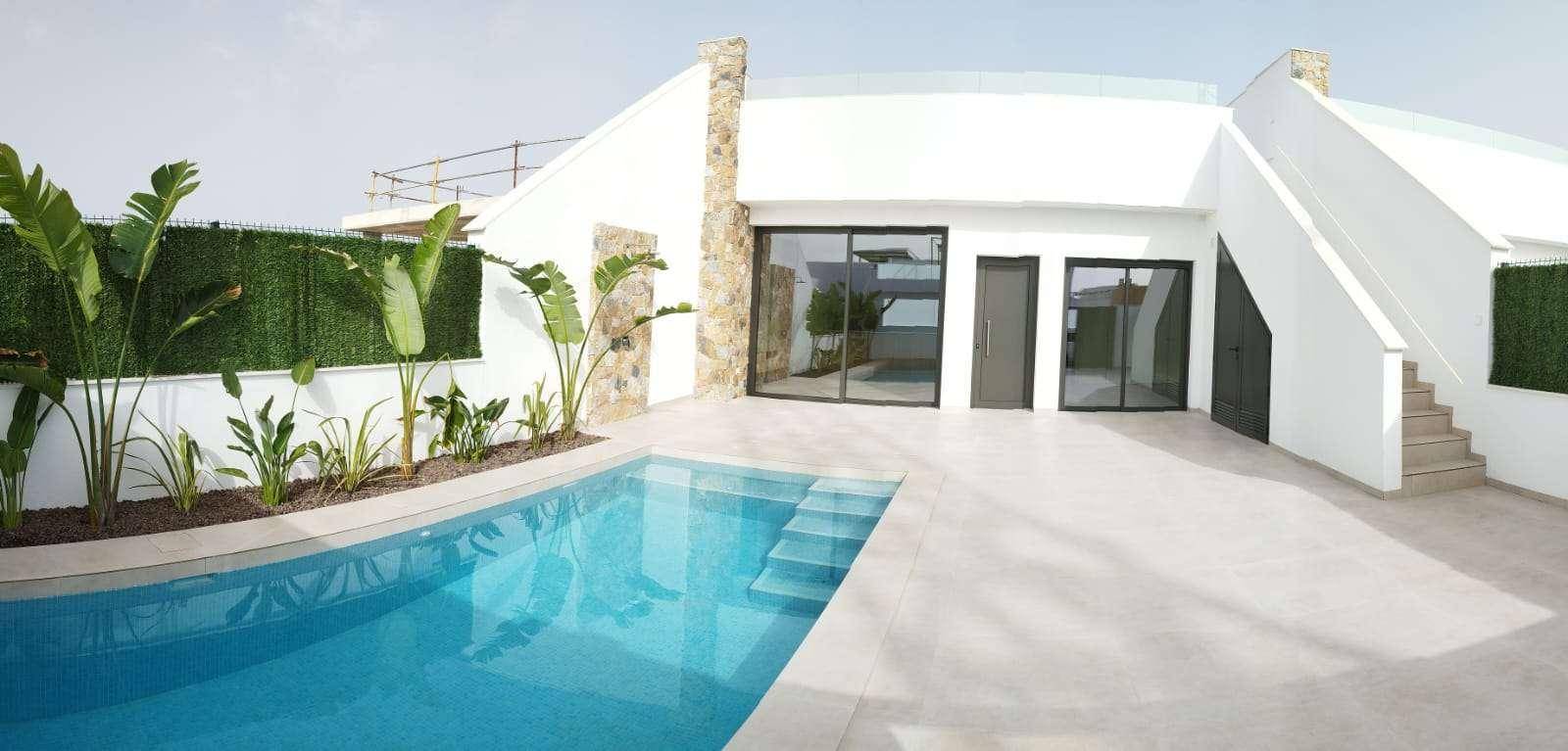 Weitläufiger Poolbereich mit moderner Architektur und üppiger Bepflanzung entlang der Mauer.