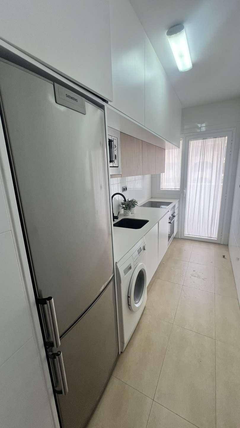 Moderne Küche mit Siemens Kühlschrank, Waschmaschine und Spüle, gut beleuchtet.