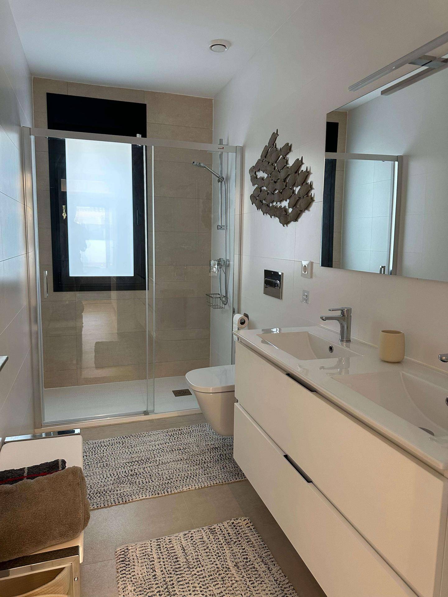 Modernes Badezimmer mit Einzelwaschbecken, großer Dusche und Fenster für Tageslicht.