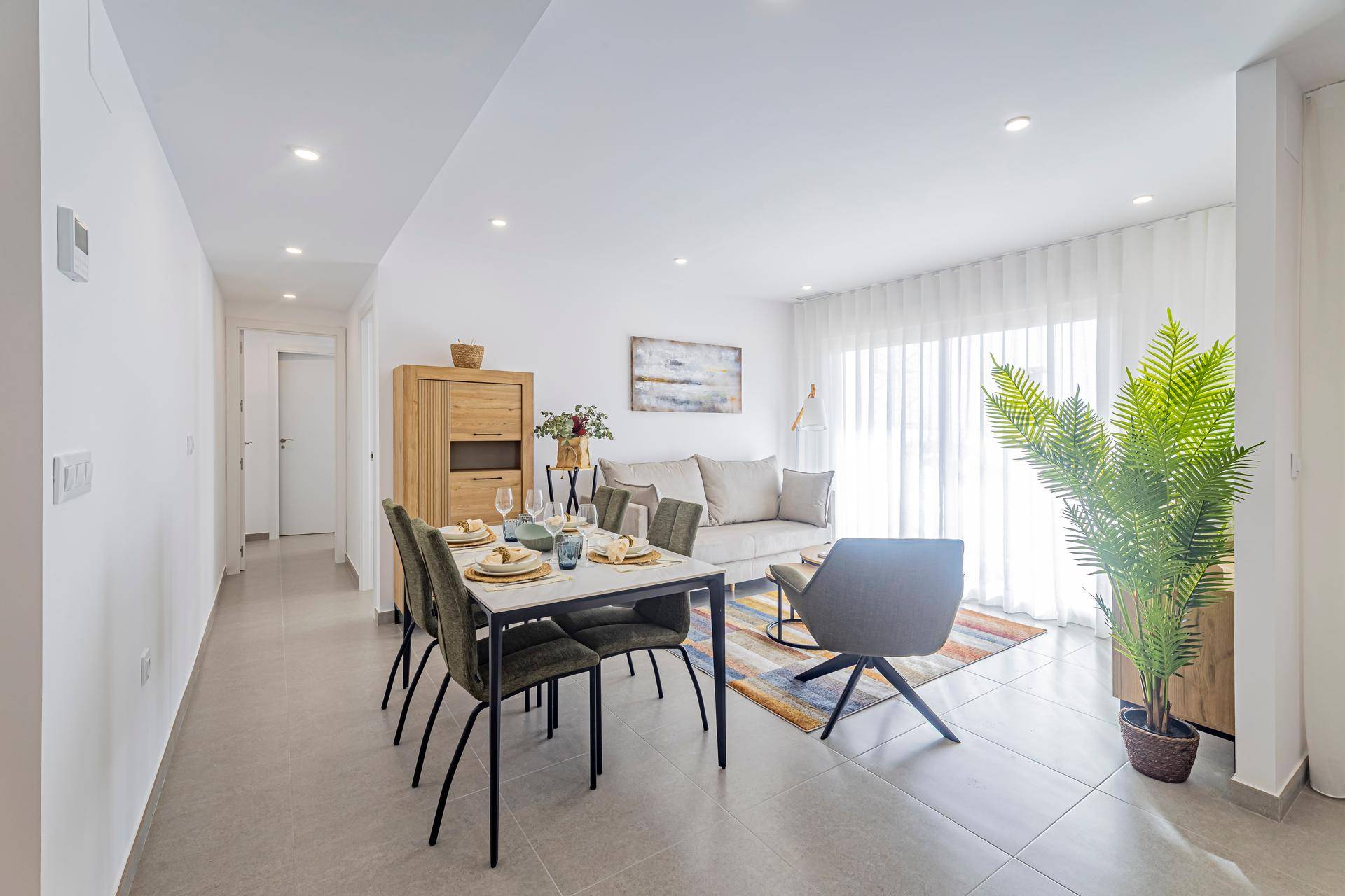 Heller Wohn- und Essbereich mit modernem Esstisch, bequemer Couch und Zugang zum Balkon.