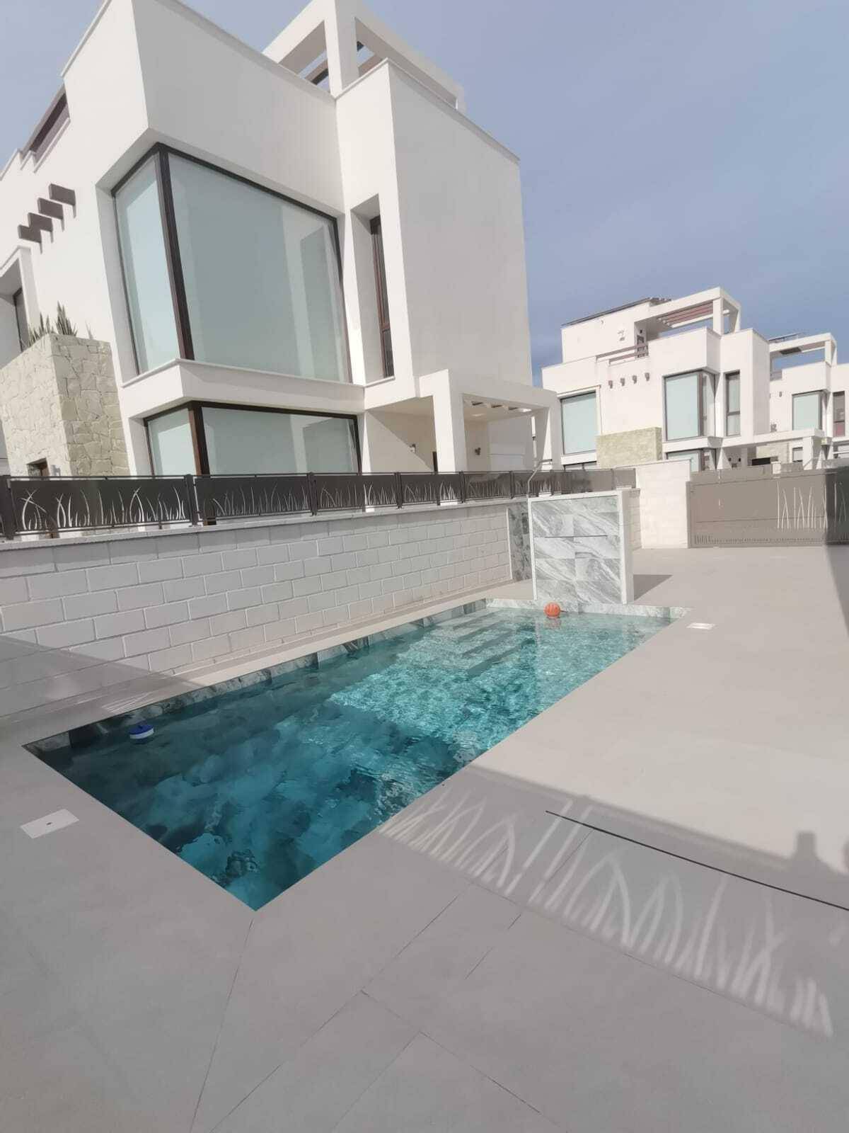 Vorderansicht des Hauses mit privatem Pool und moderner Architektur unter strahlendem Himmel.