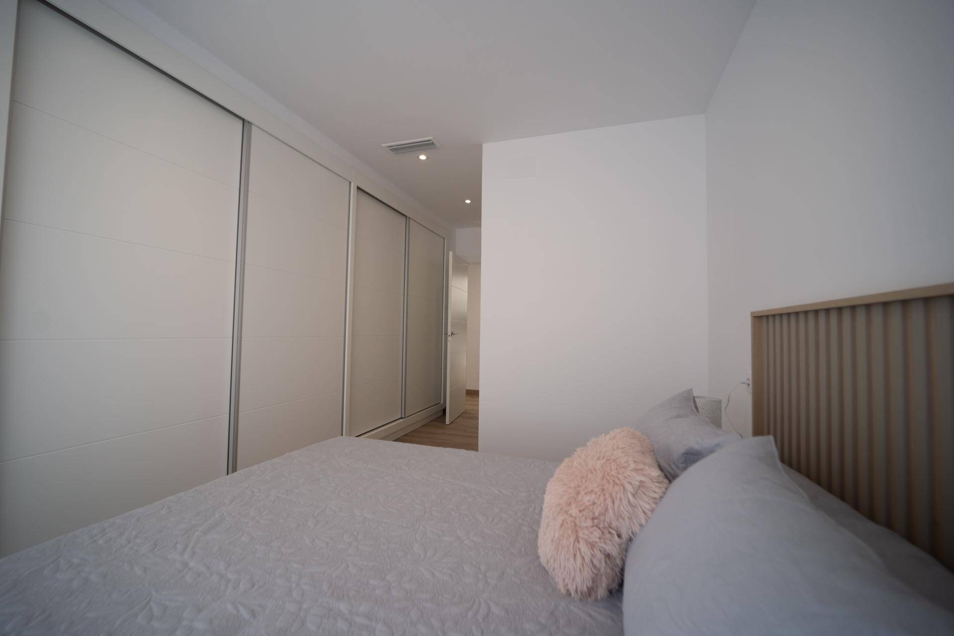 Schlafzimmer mit Doppelbett und Blick auf die modernen Einbauschränke.