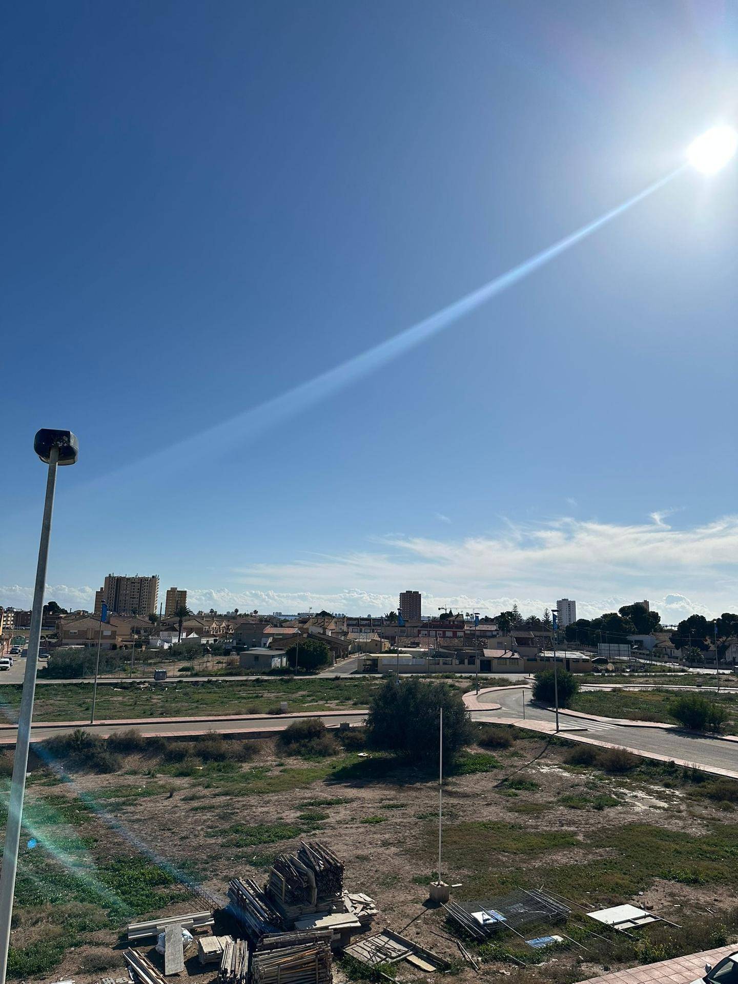 Panoramablick auf die sonnige Landschaft mit städtischen Elementen und weitem Horizont.