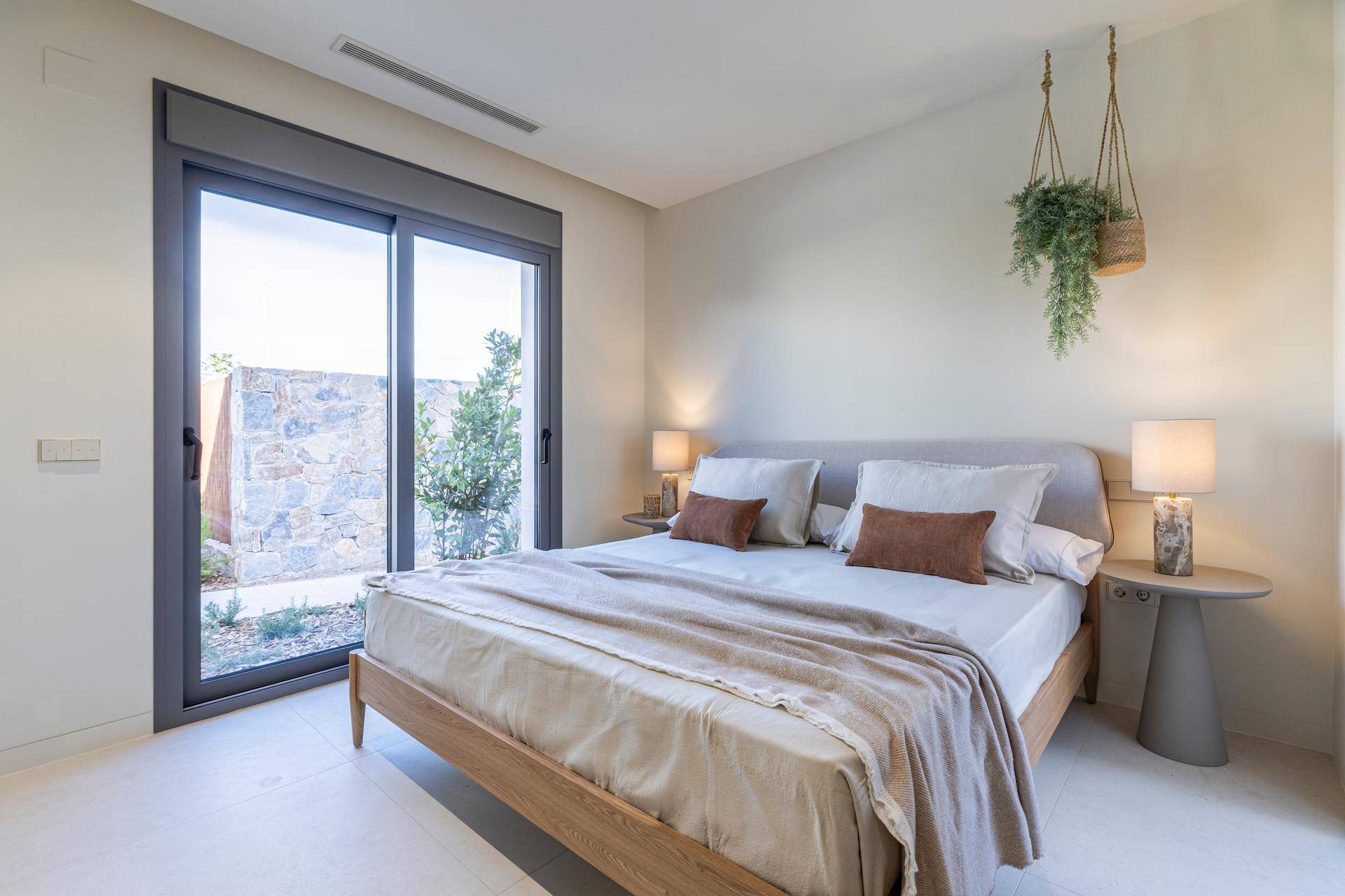 Helles Schlafzimmer mit großem Schiebefenster und Zugang zu einem kleinen privaten Außenbereich.