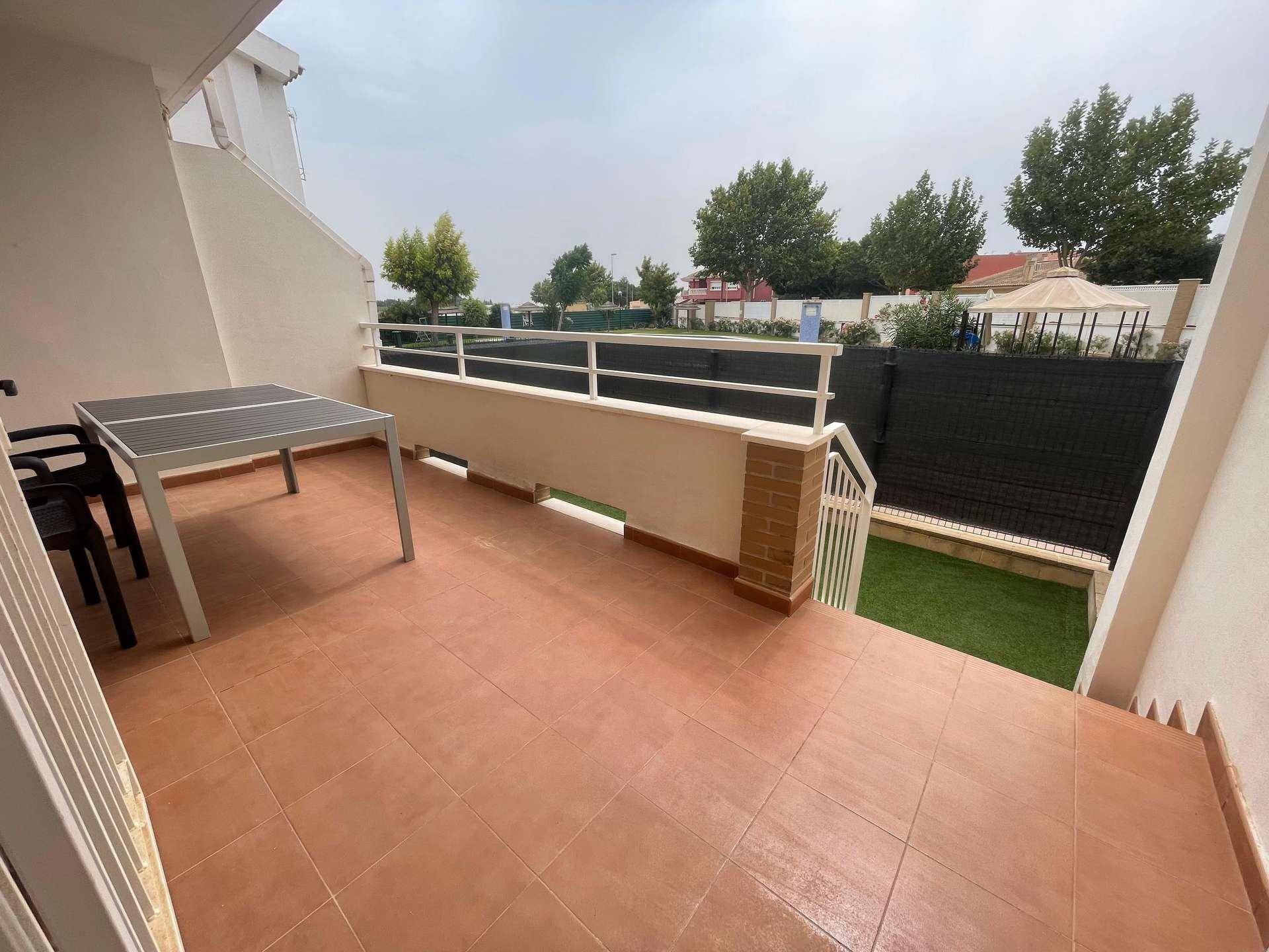 Weitläufige Terrasse mit Essbereich und Blick auf den kleinen Gartenbereich mit Kunstrasen.