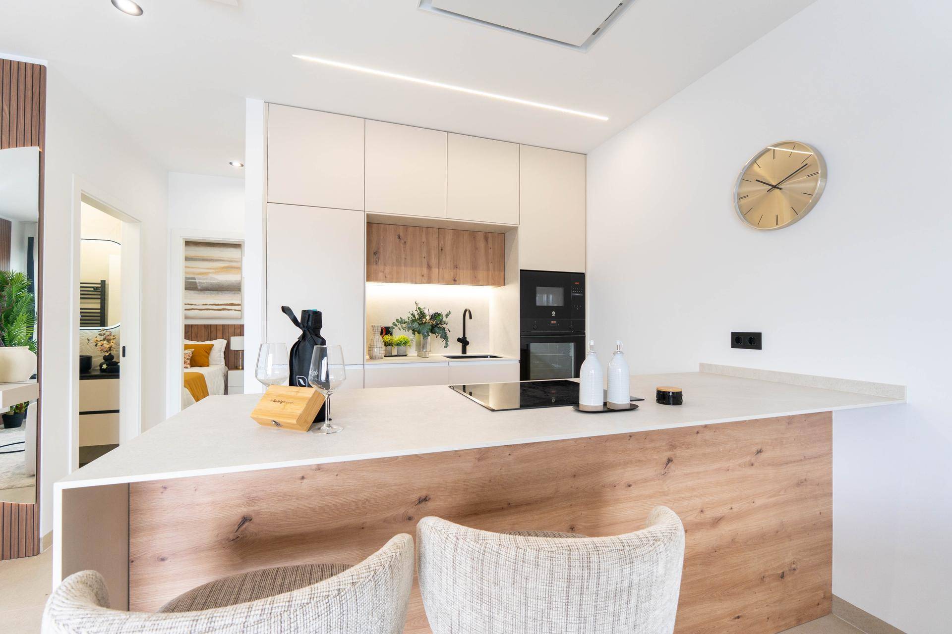 Moderne offene Küche mit Kücheninsel, integrierten Geräten und hellem Design.