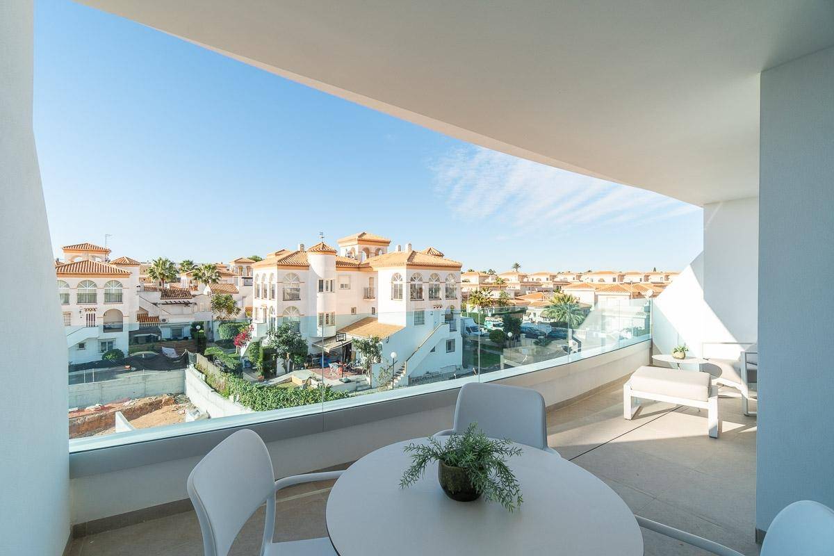 Geräumiger Balkon mit Esstisch und Stühlen, bietet einen weiten Blick auf die Wohnsiedlung.