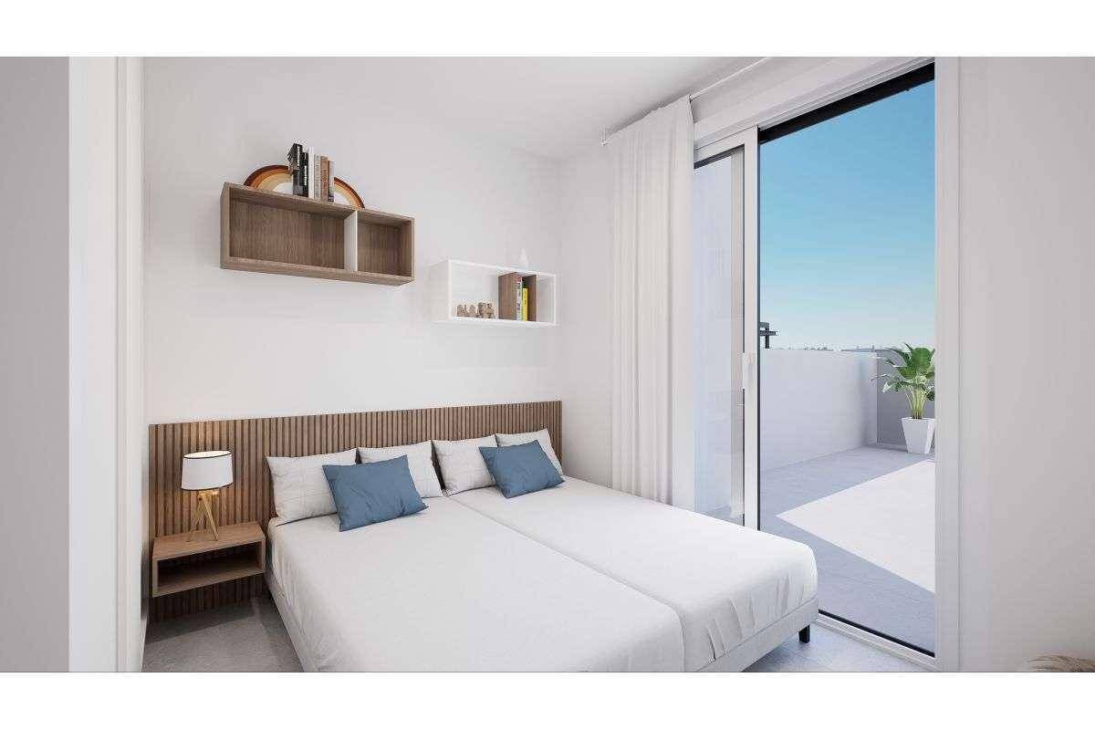 Helles Schlafzimmer mit modernem Doppelbett, Holzkopfteil und Zugang zu einer Terrasse.
