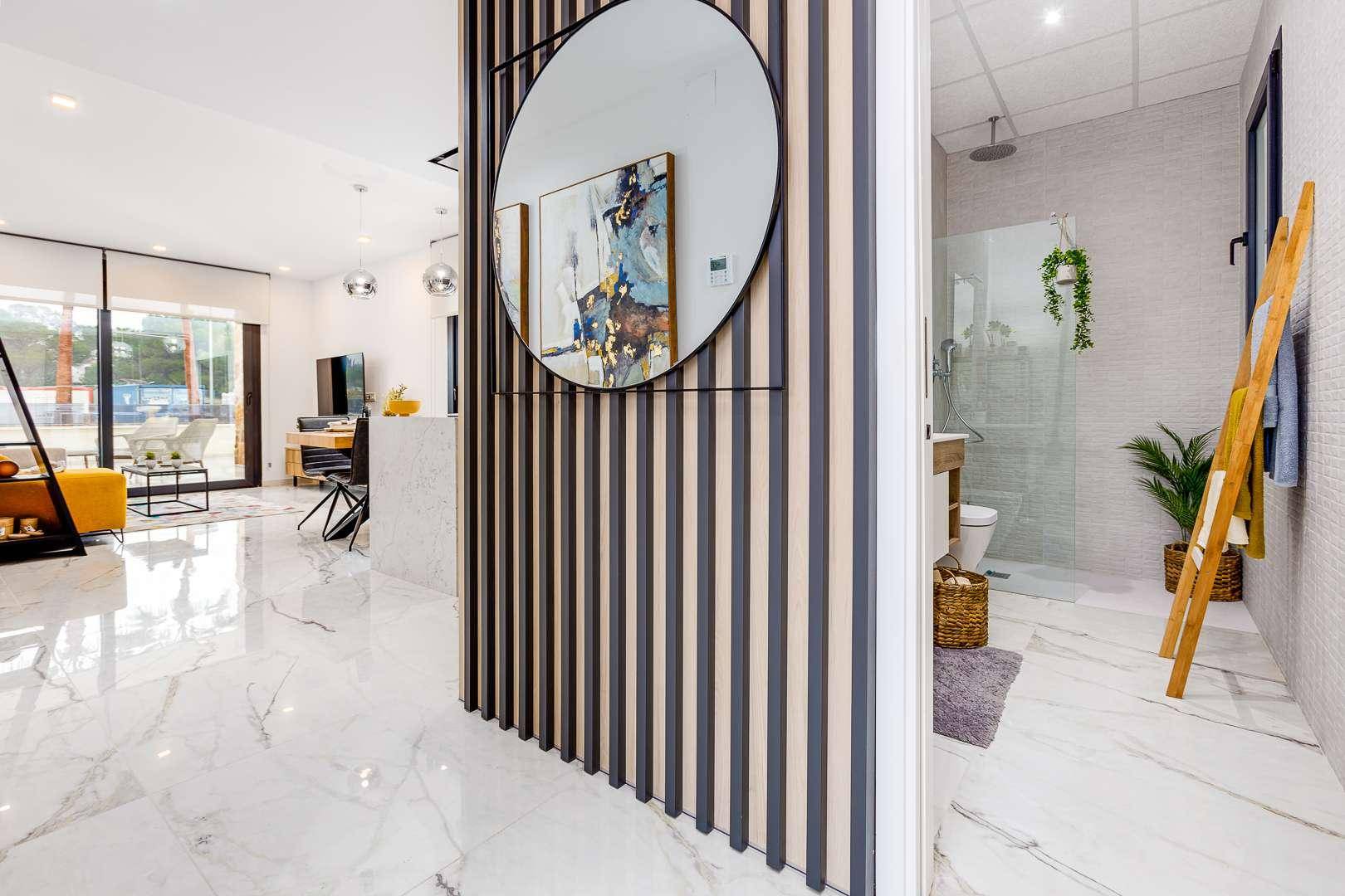 Moderner Flur mit dekorativem Spiegel und Blick in ein helles Badezimmer mit Dusche.
