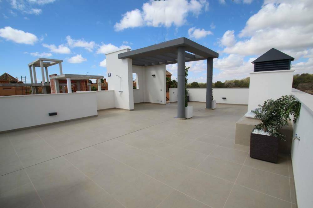 Große Dachterrasse mit Pergola, Pflanzkübeln und weitem Blick unter blauem Himmel.