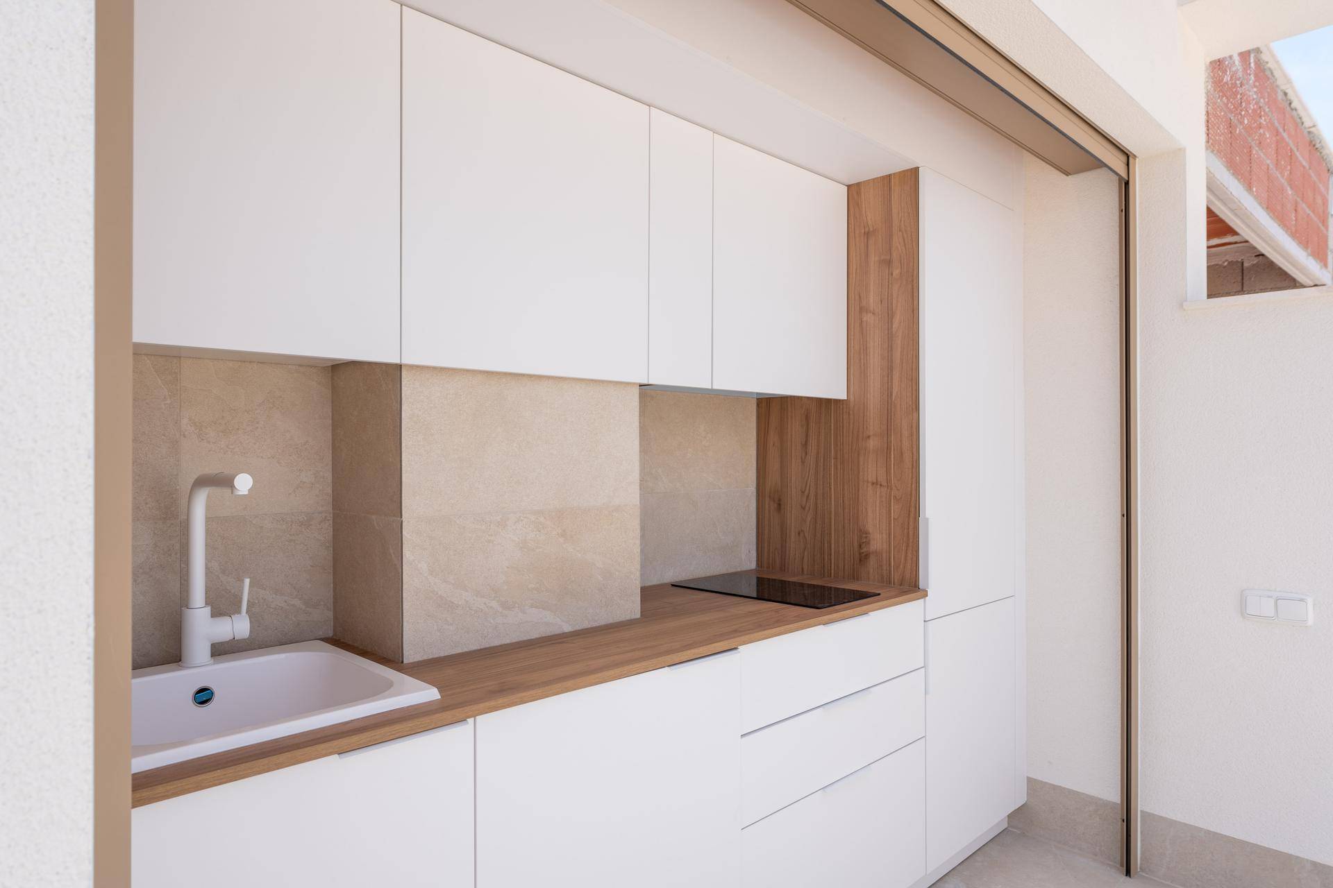Detailansicht der Außenküche mit Spüle, Induktionskochfeld und Holz-Arbeitsplatte.