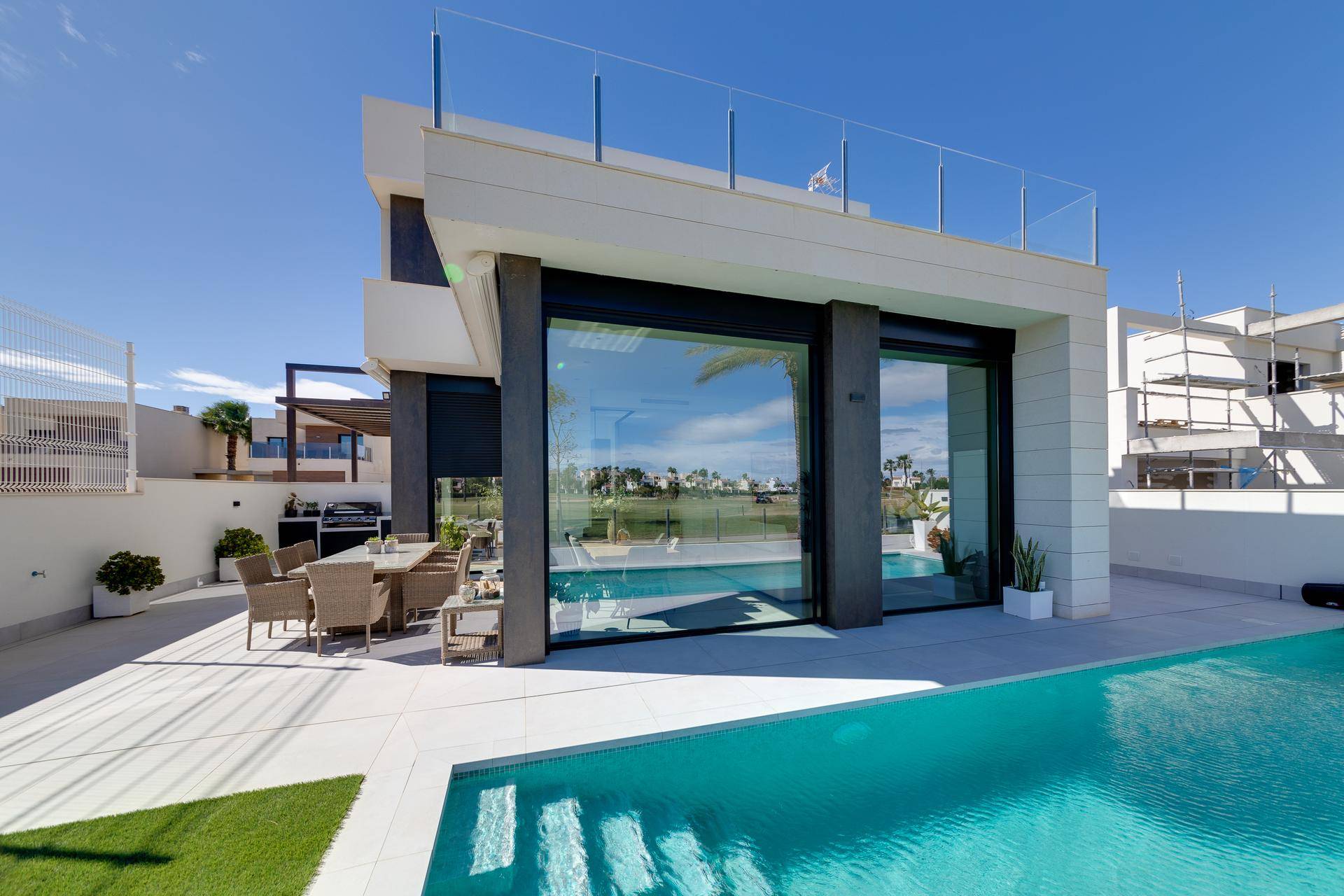 Moderne Villa mit privatem Pool und großer Terrasse, umgeben von einer gepflegten Rasenfläche.