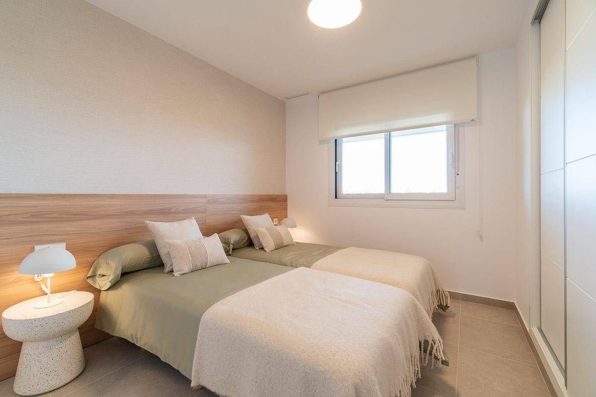 Schlafzimmer mit zwei Einzelbetten, einem Fenster und einem praktischen Einbauschrank.