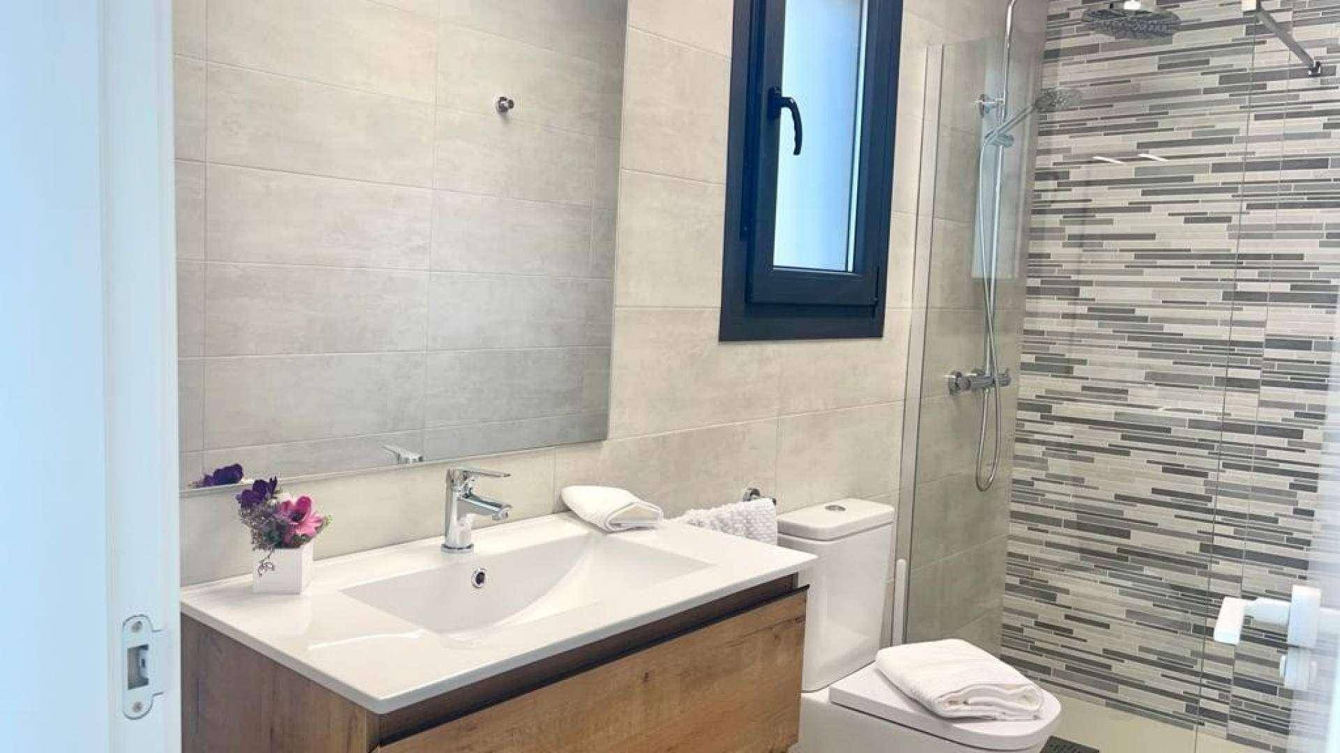 Modernes Badezimmer mit Duschkabine, Einzelwaschbecken und Fenster für natürliches Licht.