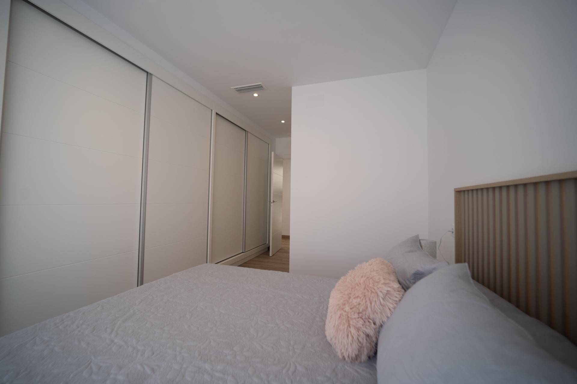 Geräumiges Schlafzimmer mit Einbauschränken, Doppelbett und hellem Laminatboden.