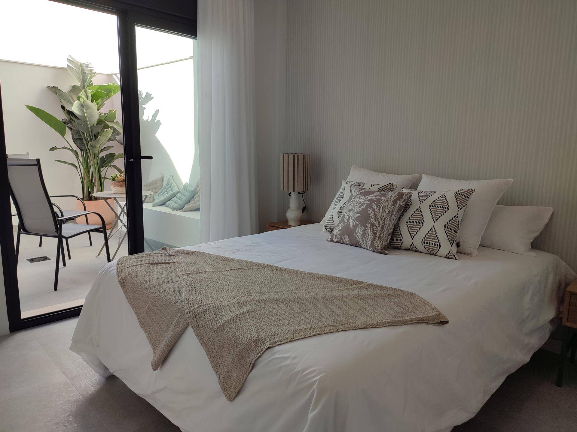 Schlafzimmer mit direktem Zugang zu einem kleinen, begrünten Innenhof und viel natürlichem Licht.