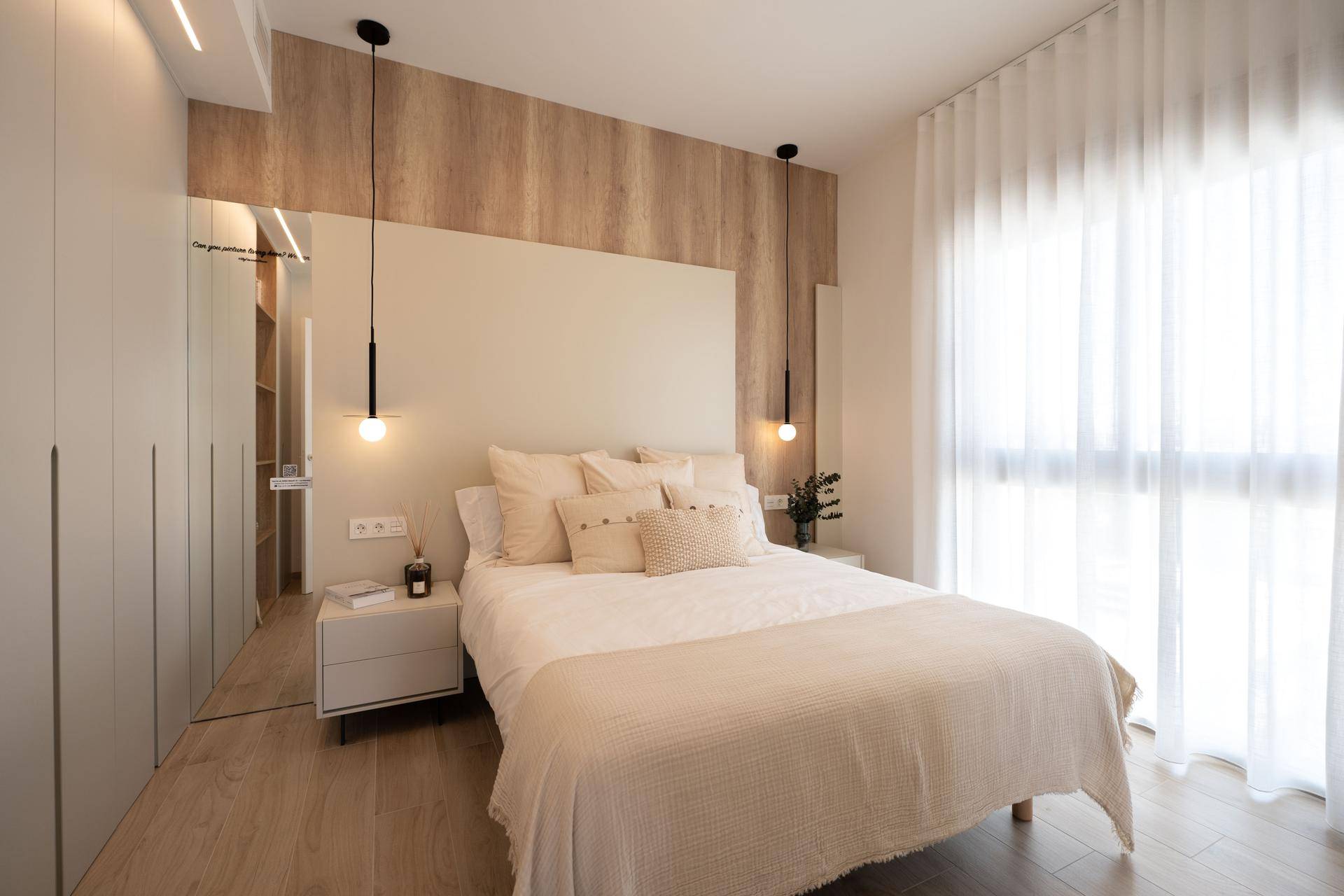 Modernes Schlafzimmer mit beigem Kopfteil, Einbauschränken und Holzboden.
