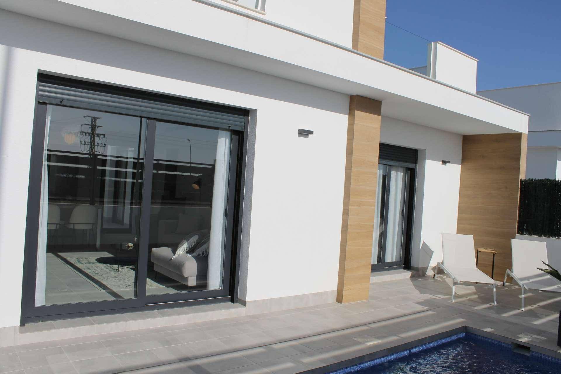 Moderne Hausfassade mit großen Schiebetüren und einem sonnigen Poolbereich.
