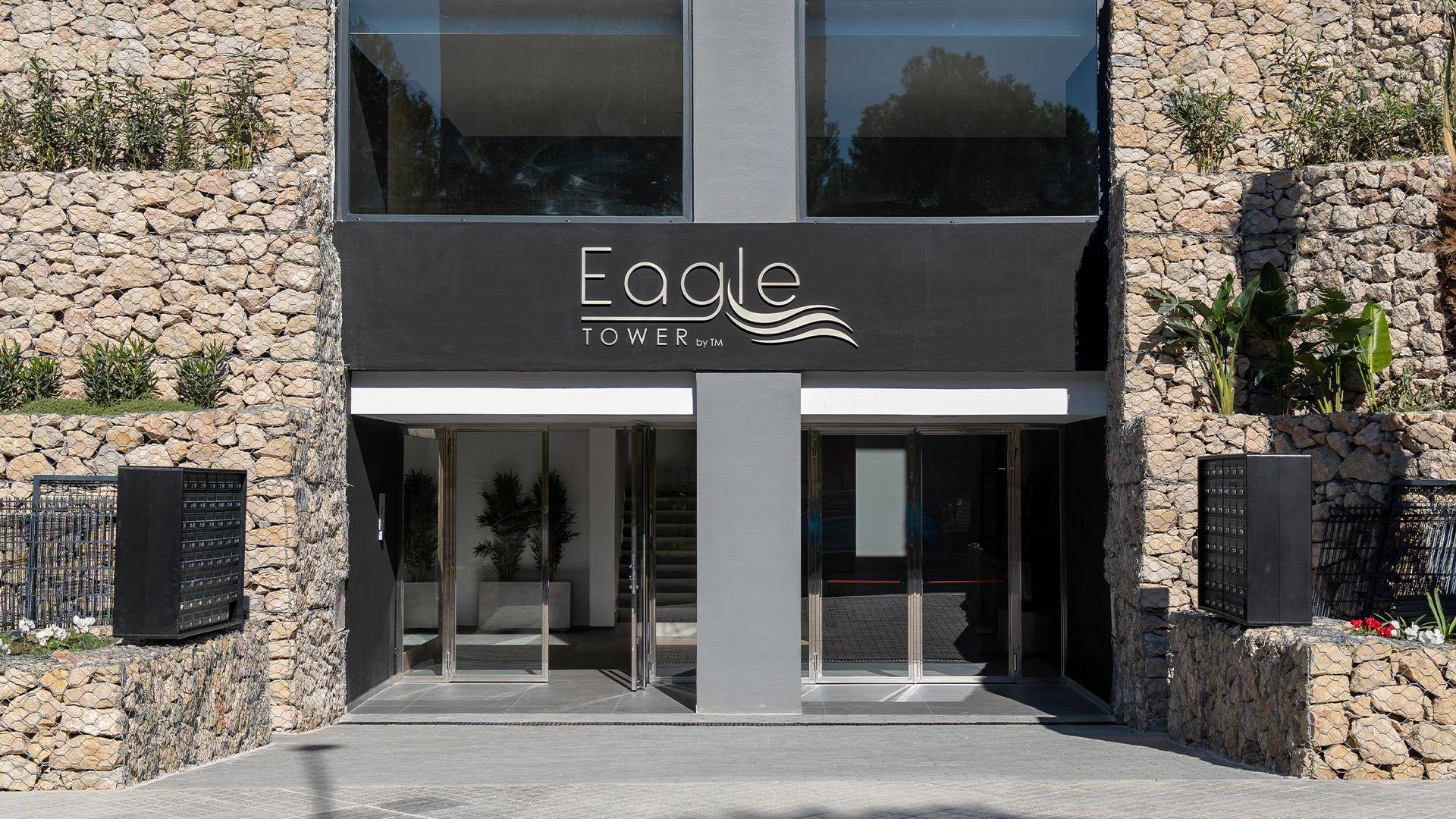 Eingangsbereich des modernen Gebäudes mit Steinverkleidung und dem Schriftzug "Eagle Tower".