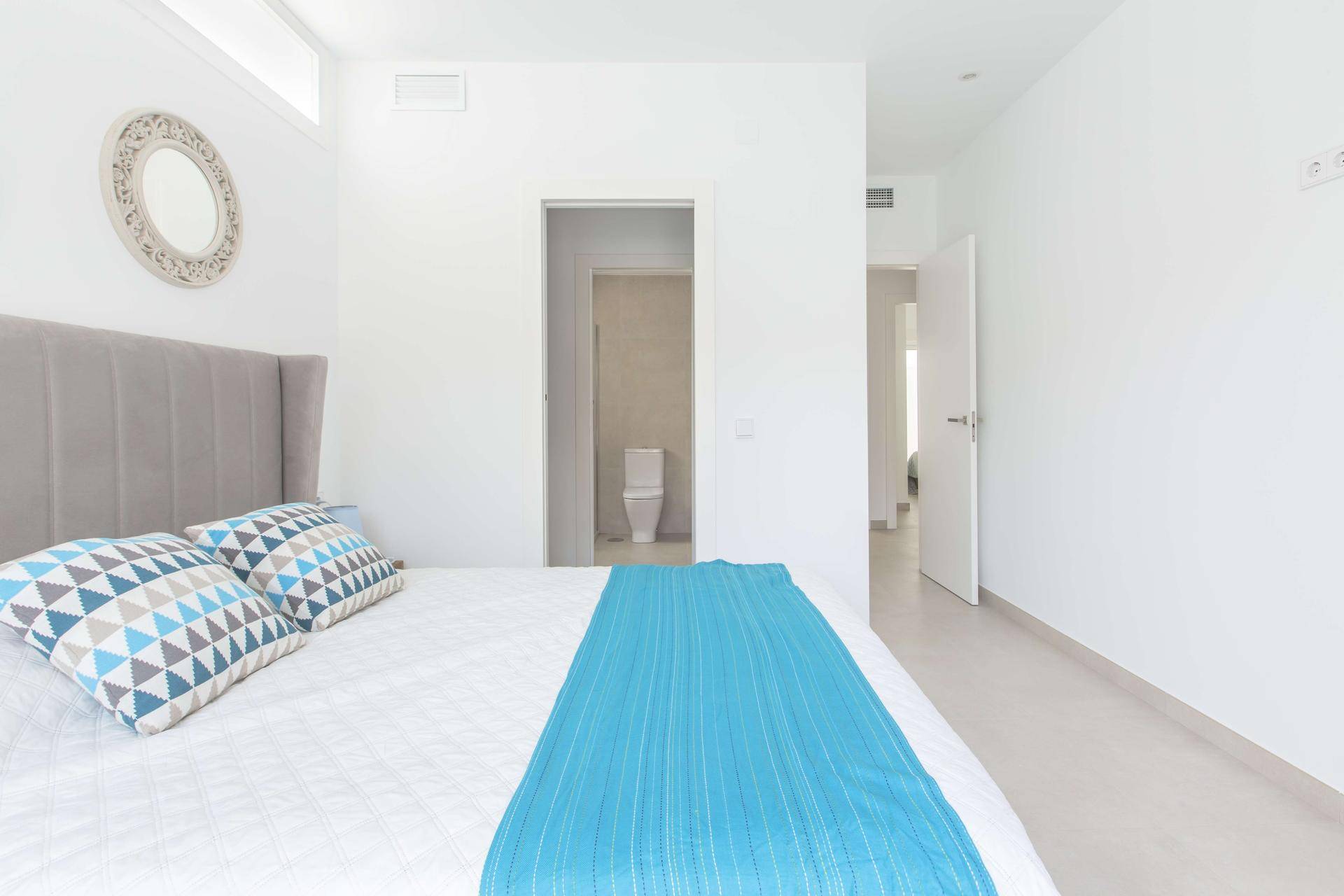 Helles Schlafzimmer mit Doppelbett und direktem Zugang zu einem angrenzenden Badezimmer.