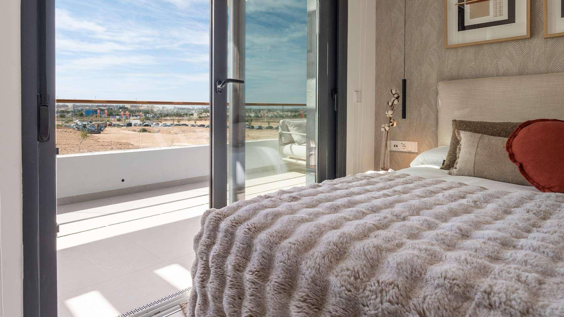 Gemütliches Schlafzimmer mit Doppelbett und direktem Zugang zu einem sonnigen Balkon.