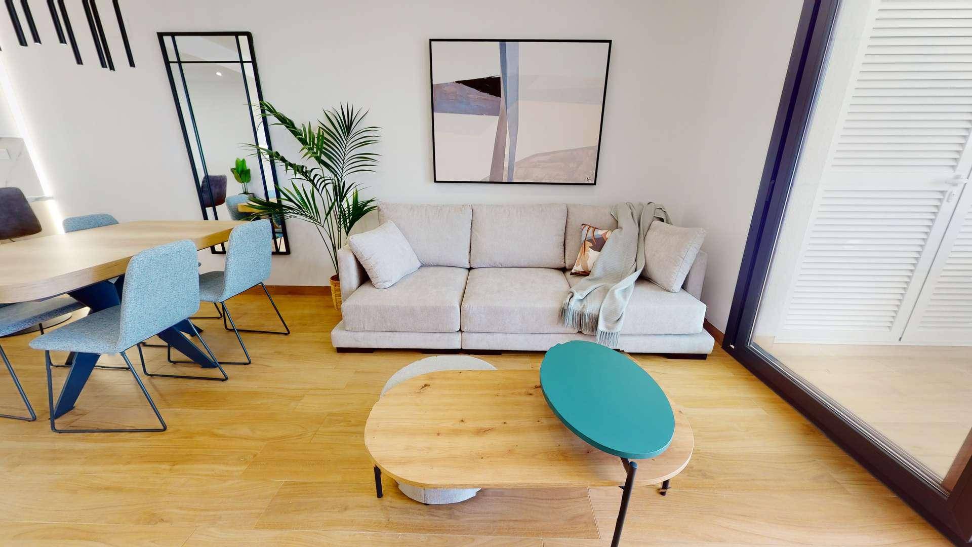 Gemütlicher Wohnbereich mit Sofa, Couchtisch und Zugang zu einem sonnigen Außenbereich.