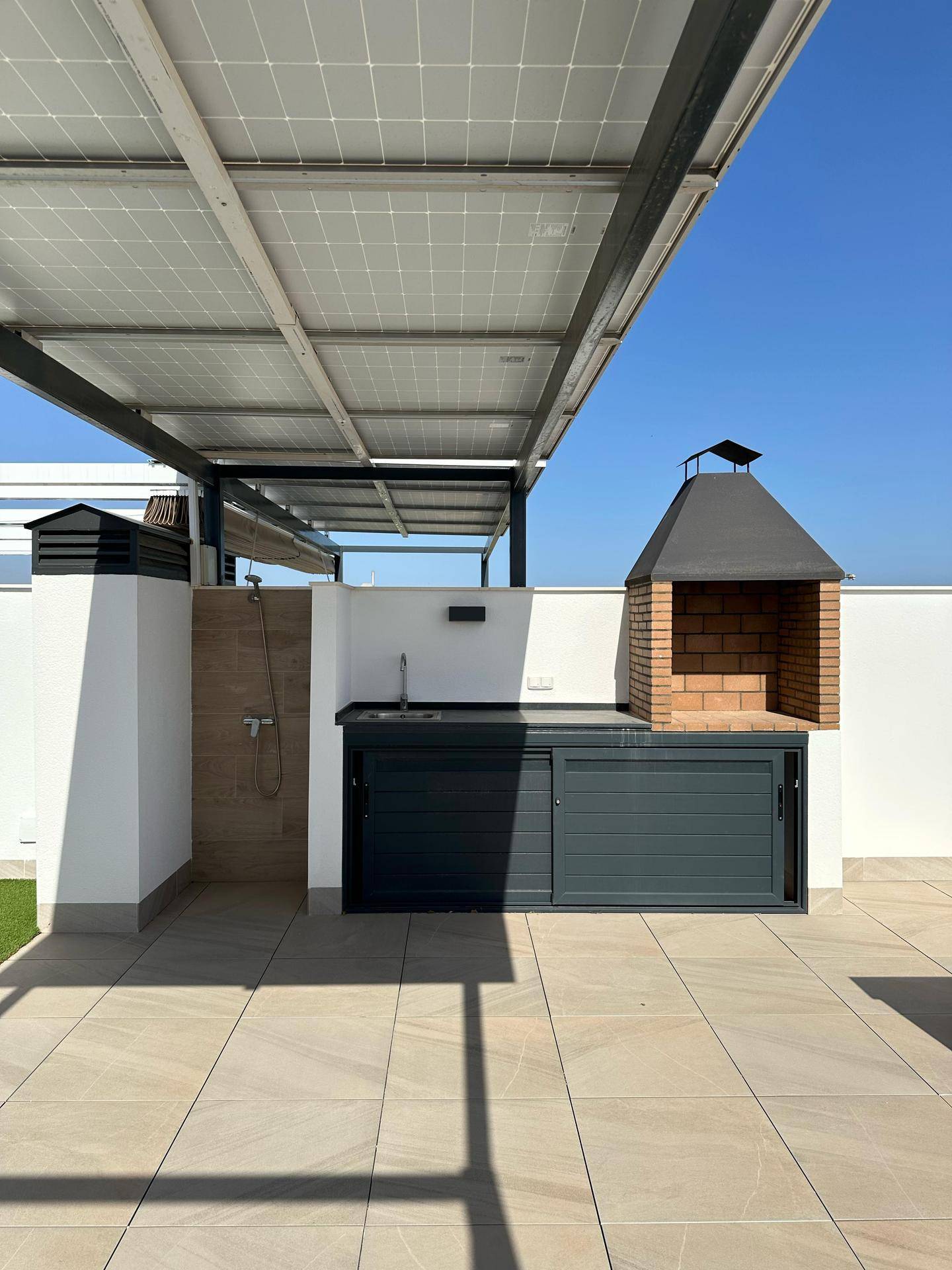 Detailansicht der Außenküche auf der Dachterrasse mit gemauertem Grill und Spülbecken.