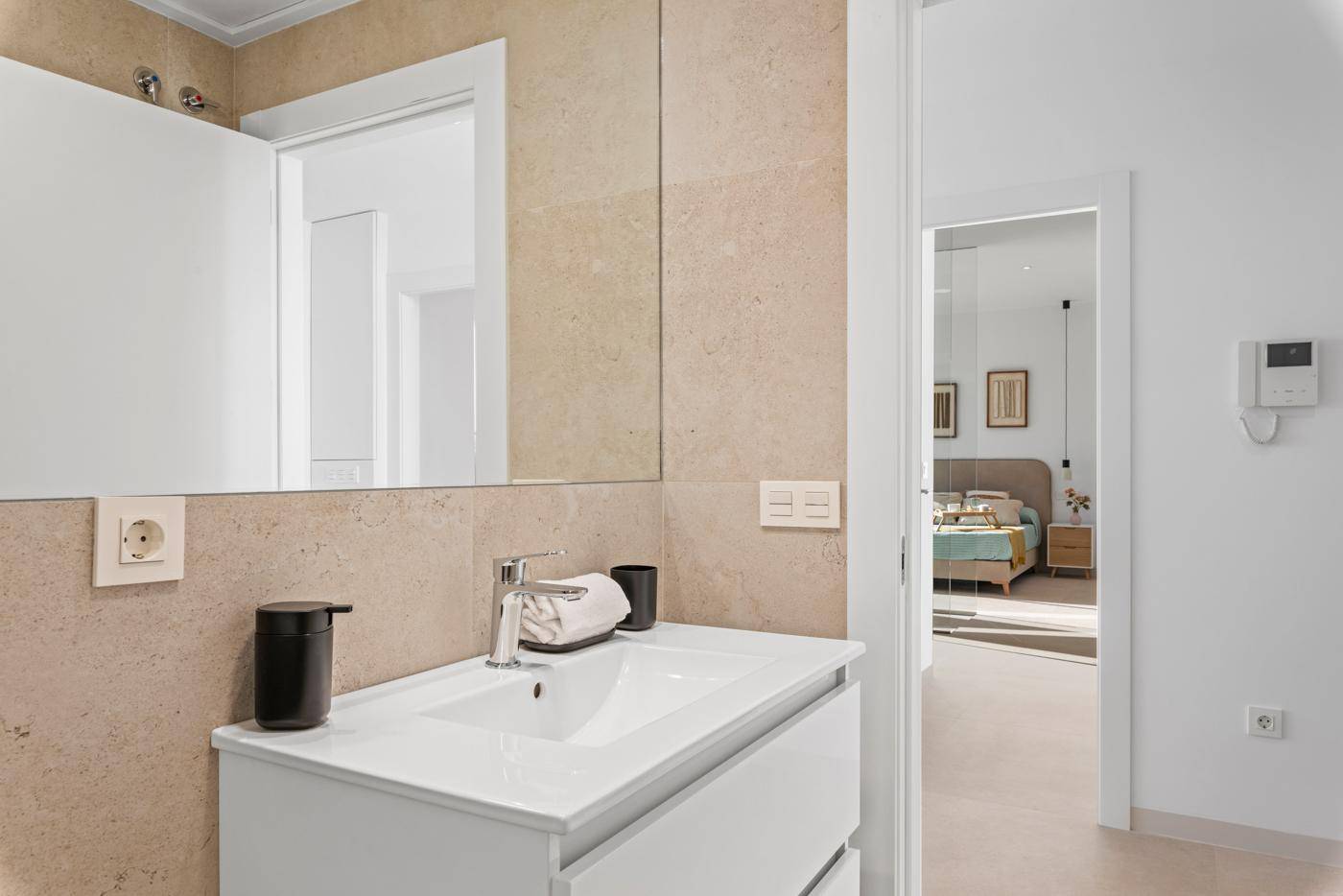 Modernes Badezimmer mit Einzelwaschbecken und großem Spiegel, angrenzend an ein Schlafzimmer.