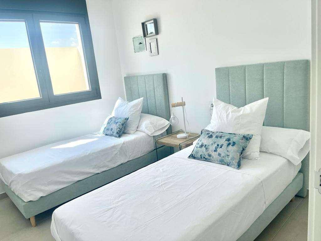 Helles Schlafzimmer mit zwei Einzelbetten, modernem Design und großem Fenster.