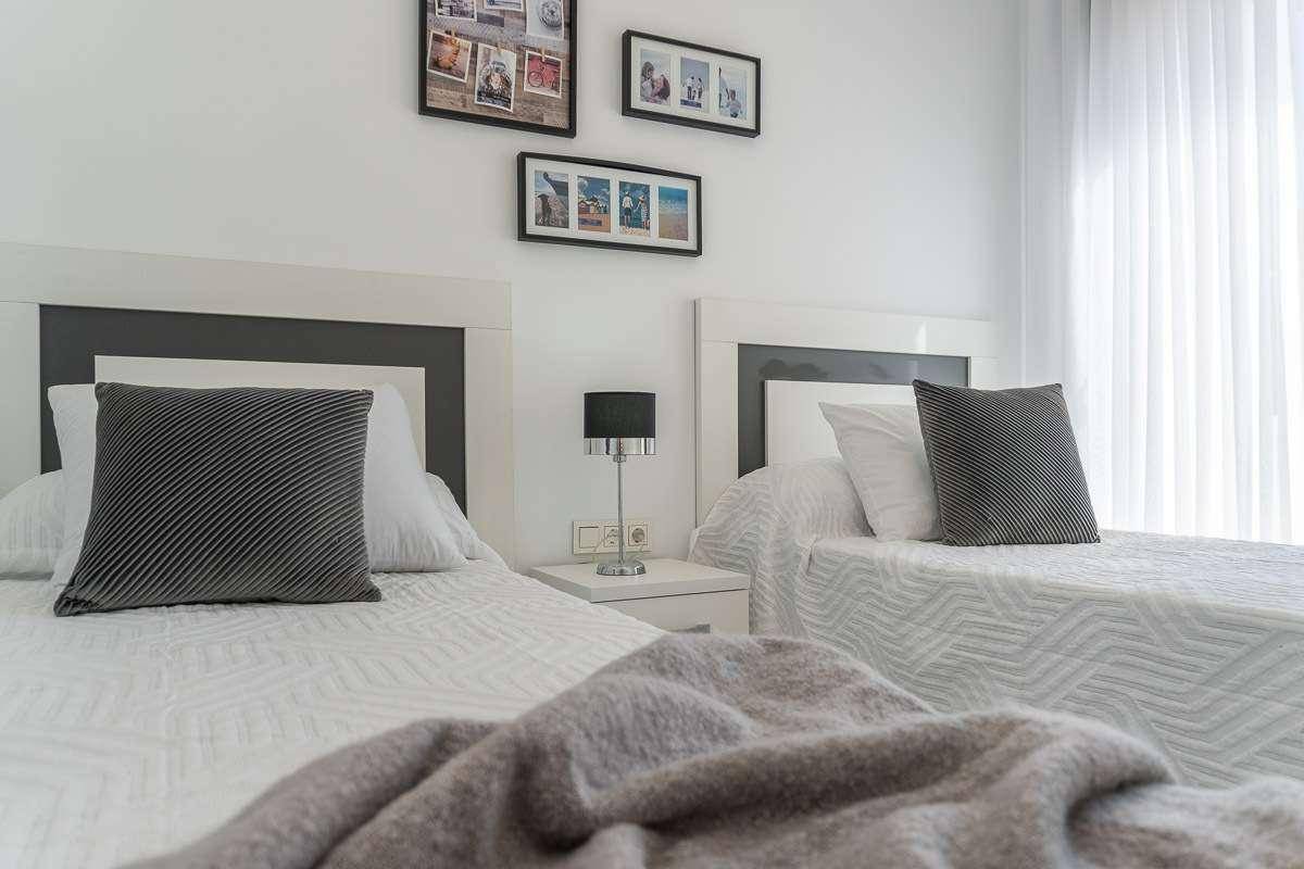 Helles Schlafzimmer mit zwei Einzelbetten, modernen Nachttischen und Fenster.
