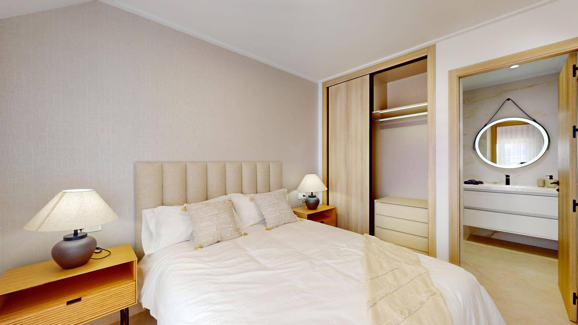 Modernes Schlafzimmer mit Einbauschrank und Zugang zu einem hellen Badezimmer.