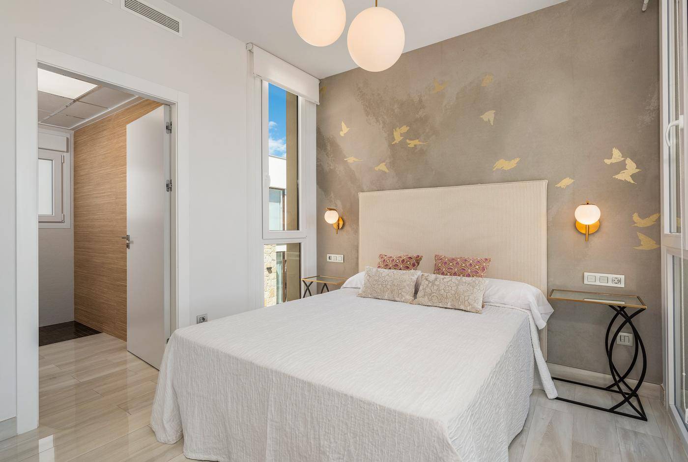 Elegantes Schlafzimmer mit Doppelbett, dekorativer Wandgestaltung und viel natürlichem Licht.