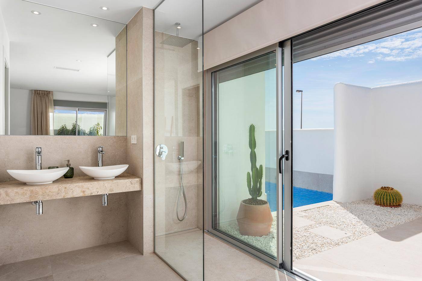 Modernes Badezimmer mit Doppelwaschbecken, begehbarer Dusche und Poolblick.