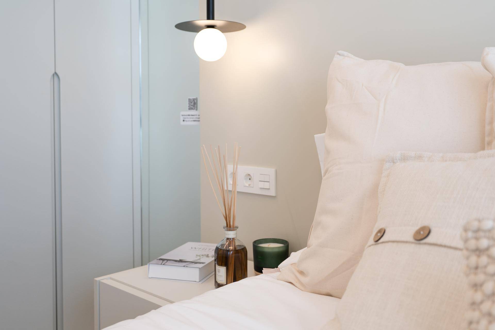 Detailansicht des Nachttisches mit Beleuchtung und Dekoration im modernen Schlafzimmer.