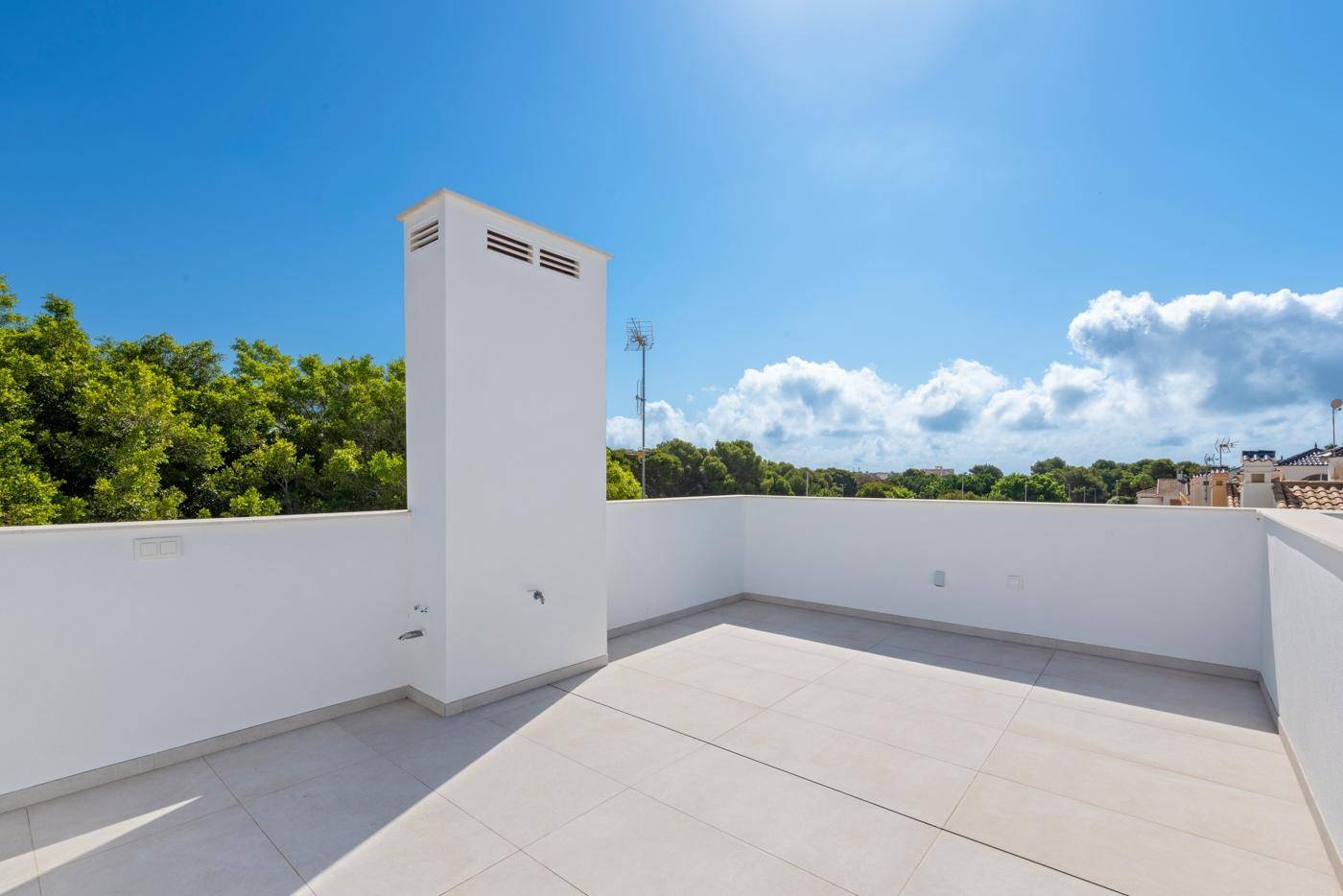 Große, unmöblierte Dachterrasse mit weitem Blick unter blauem Himmel.