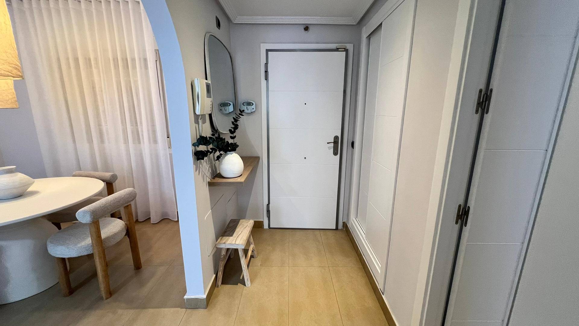 Moderner Eingangsbereich mit weißer Tür, Einbauschrank und hellem Fliesenboden.